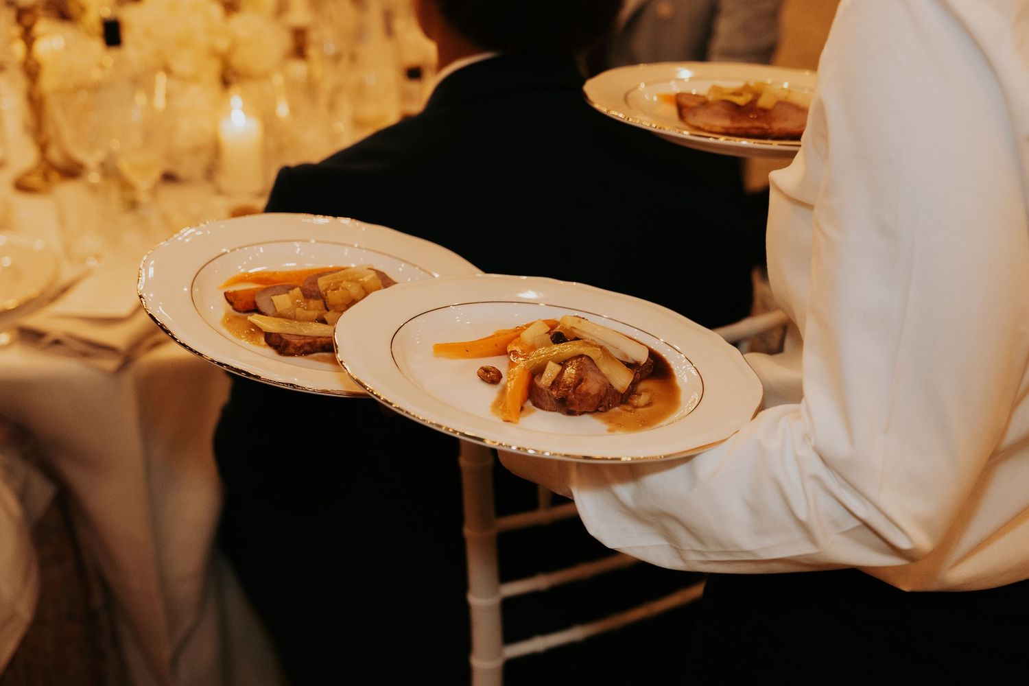 Elegant table settings with glowing candles and wine glasses create an intimate wedding reception atmosphere.