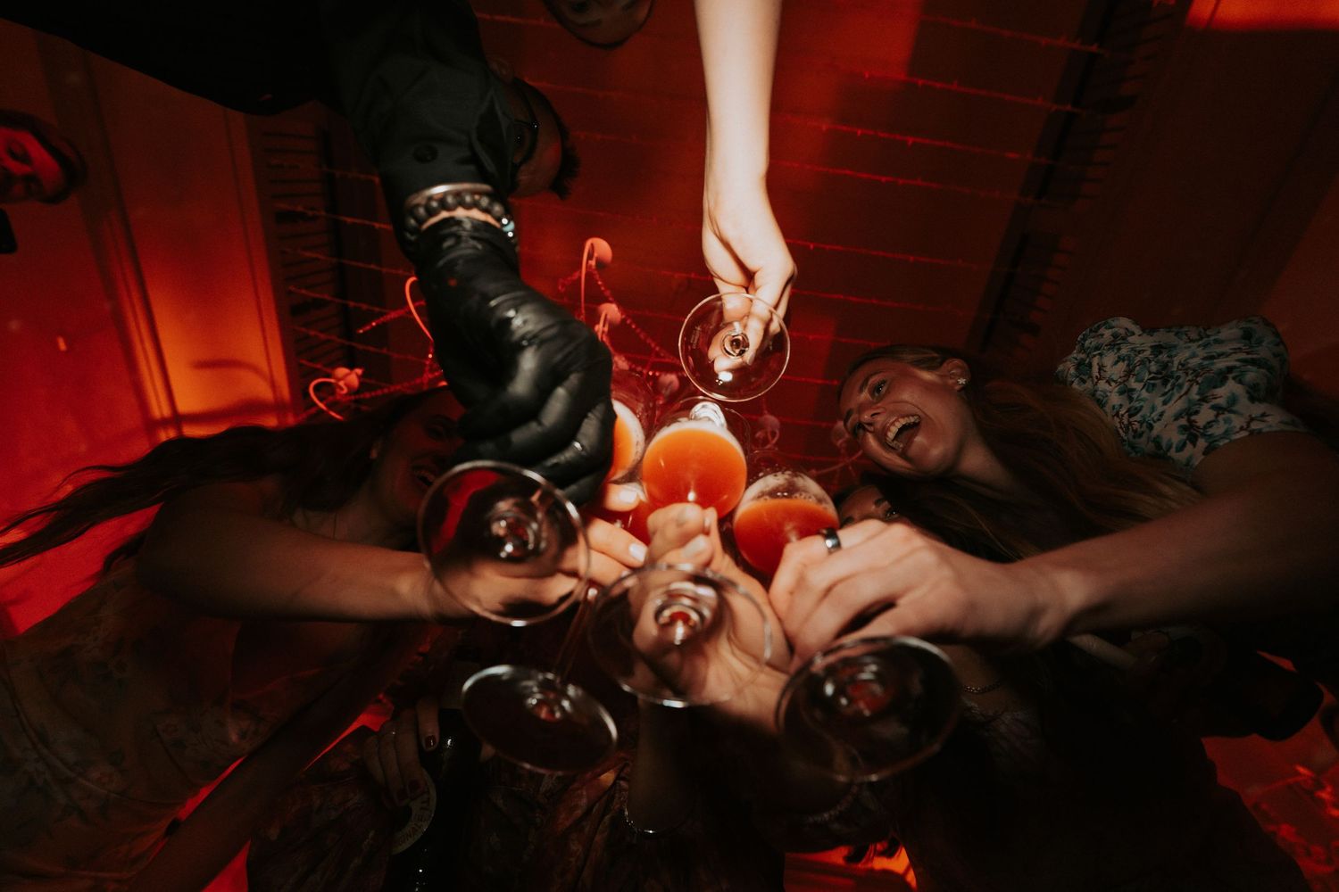 Red-lit dance floor creates dramatic atmosphere during wedding reception celebrations.