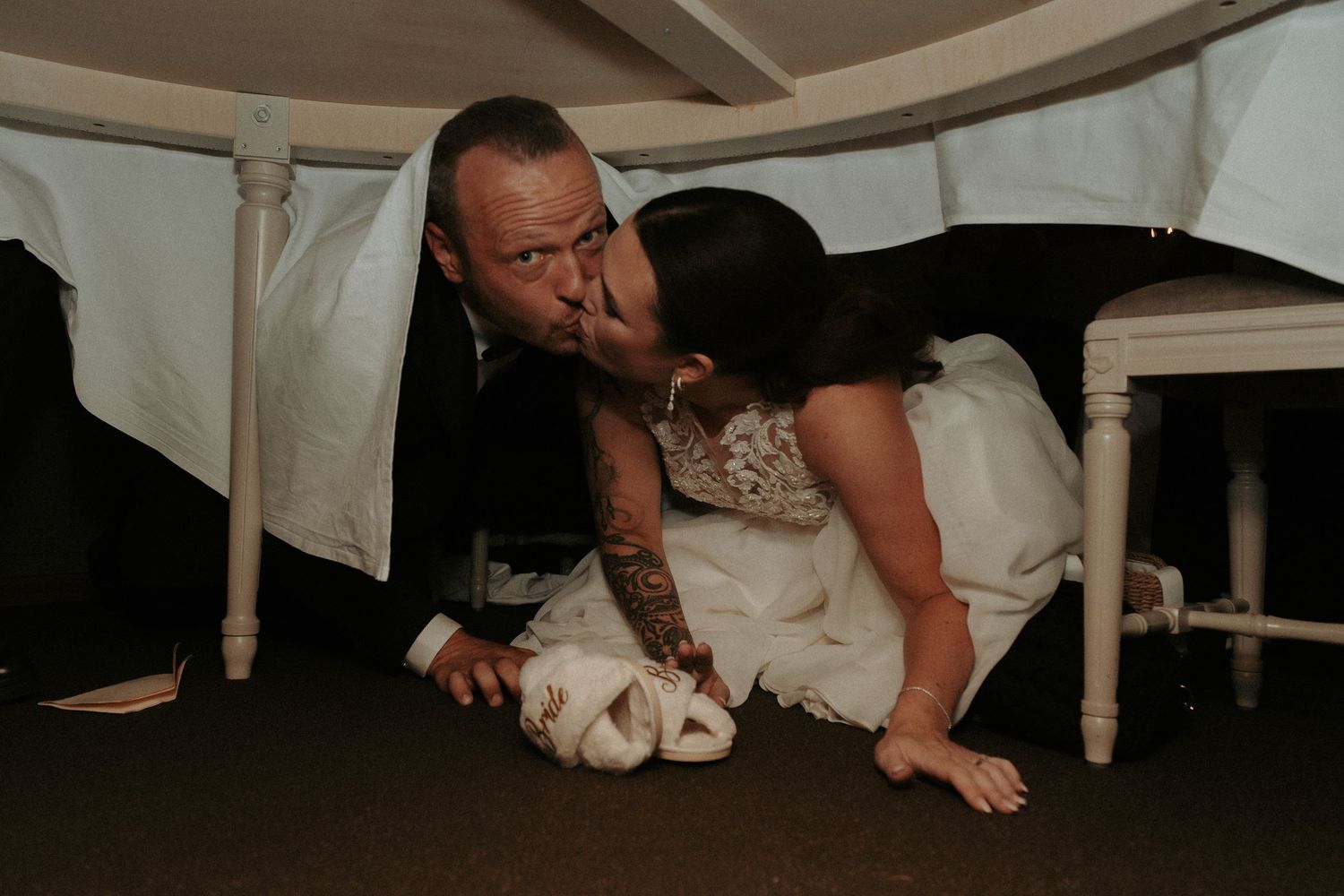 Playful moment under a table during wedding reception.