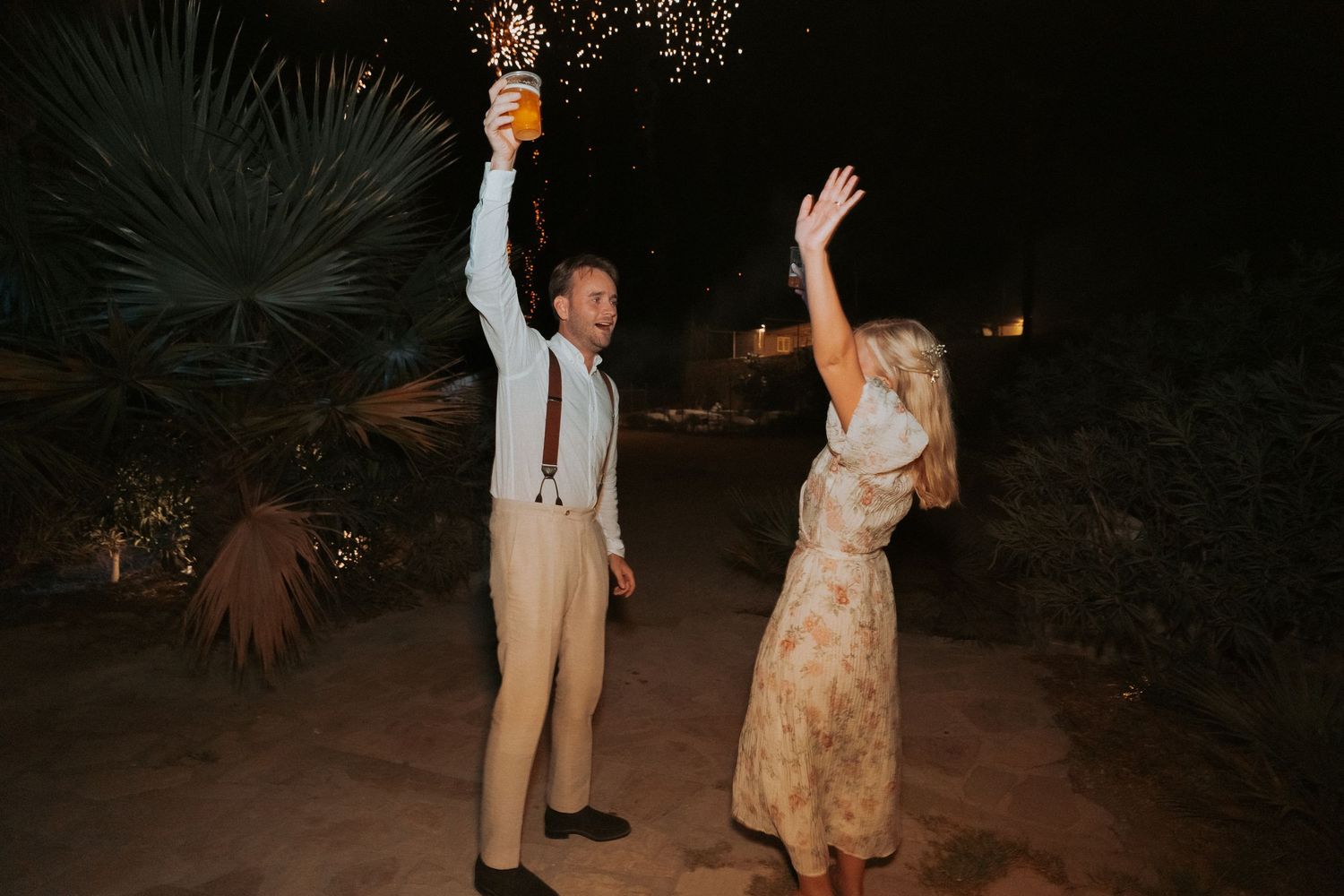 Couple dancing under string lights at night during outdoor wedding celebration.