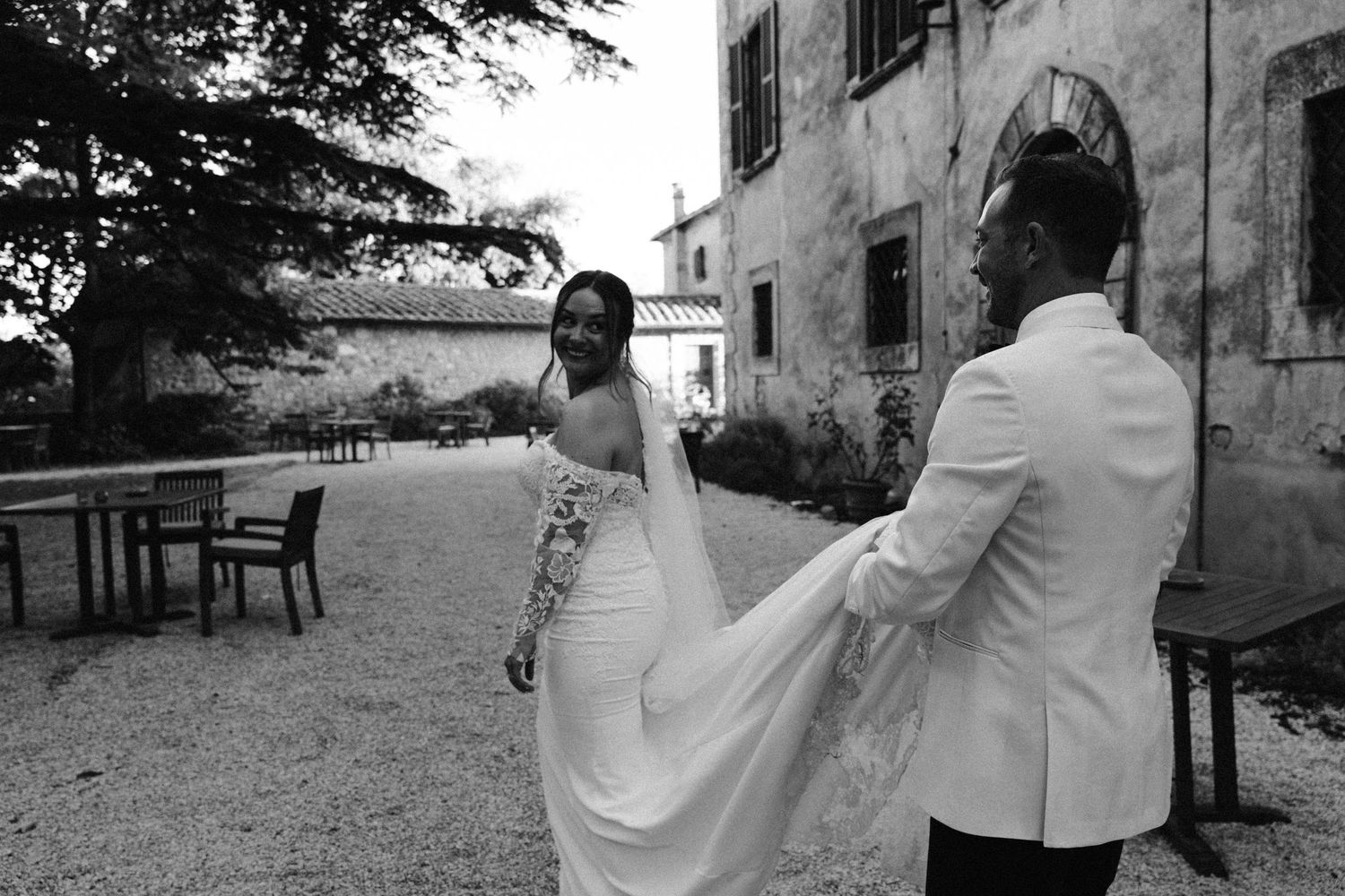 Black and white photo of a couple enjoying a playful moment in their wedding attire.