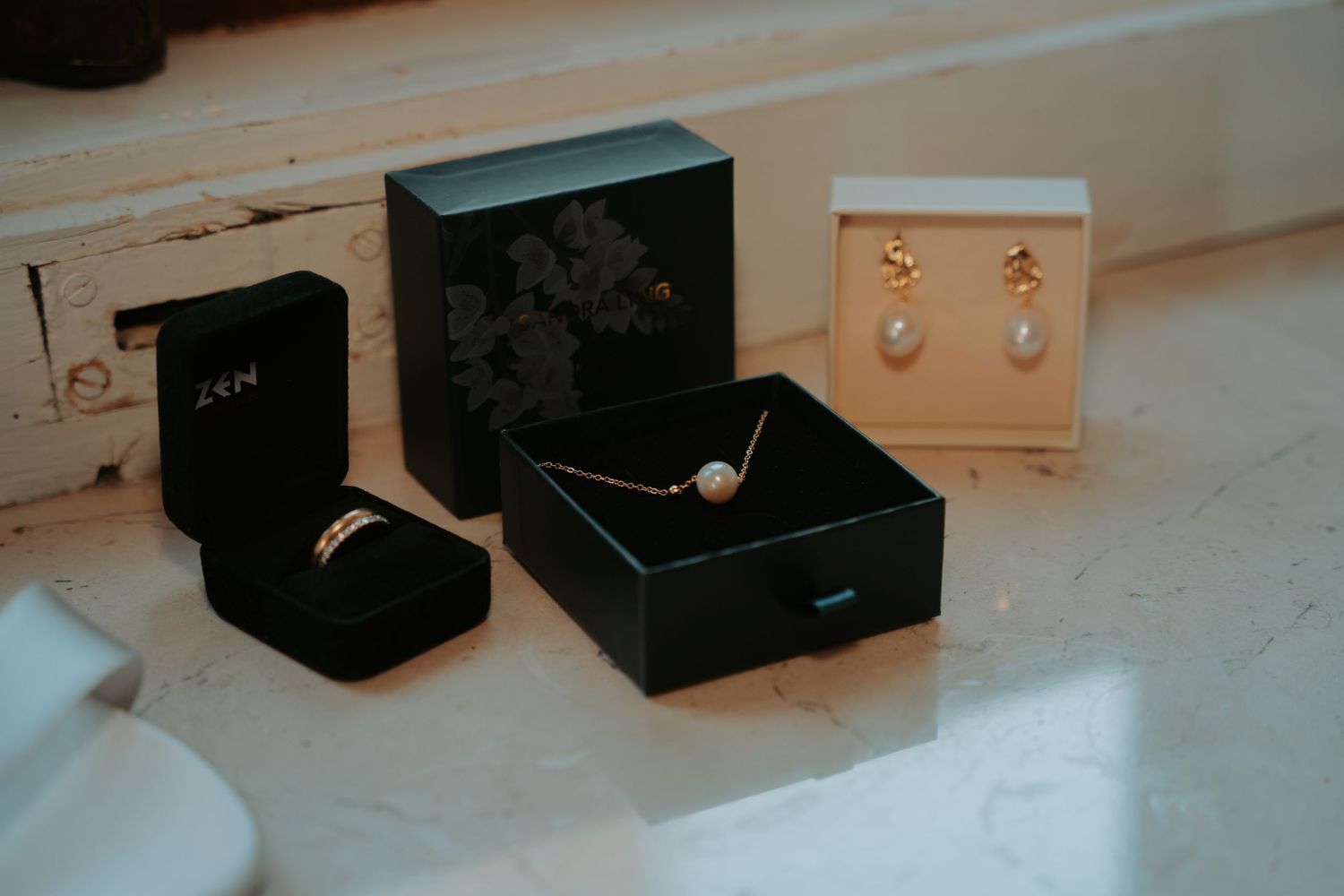Collection of small black jewelry boxes arranged on a white surface in natural light.