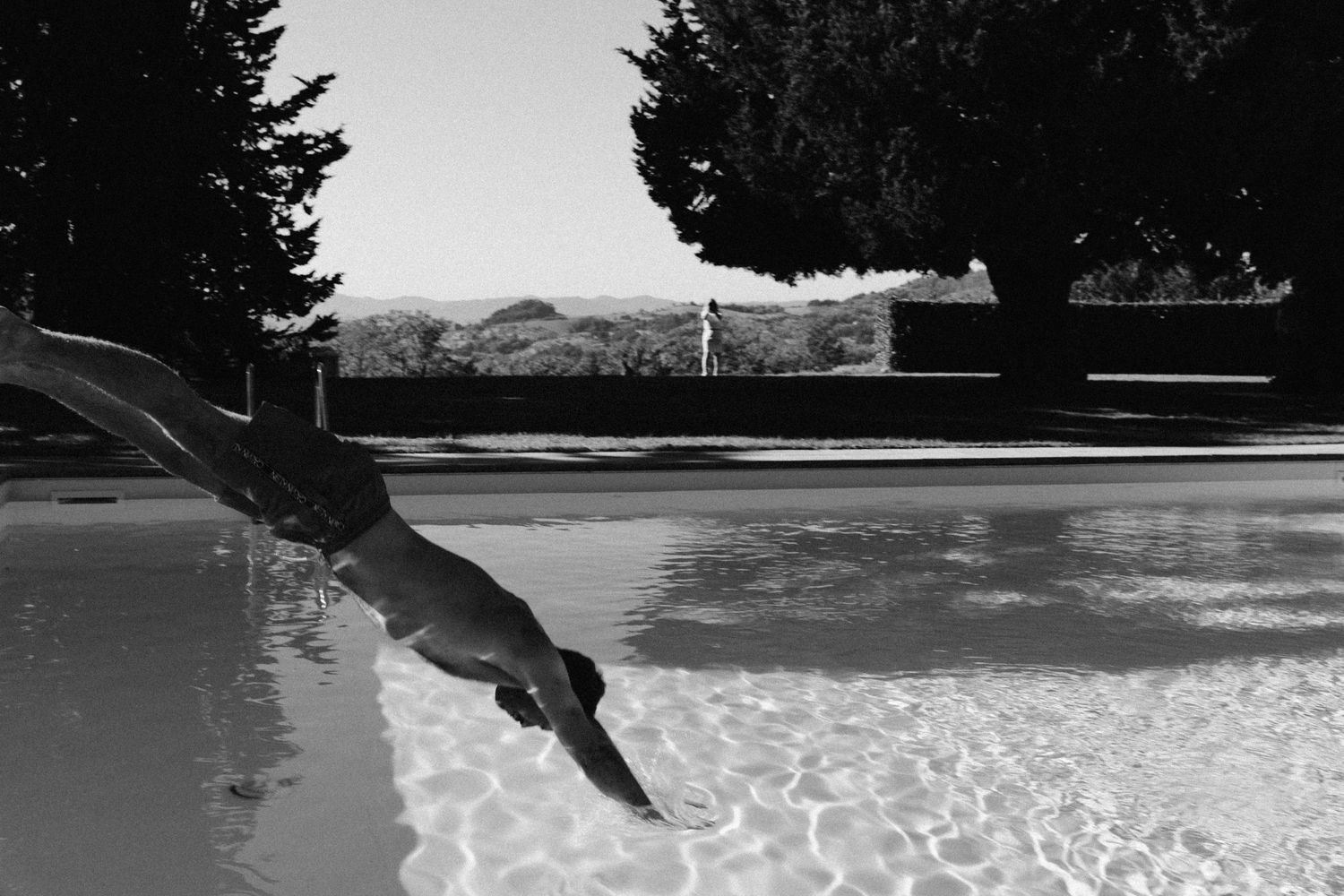Black and white photos of swimmers diving into a pool in sequence.