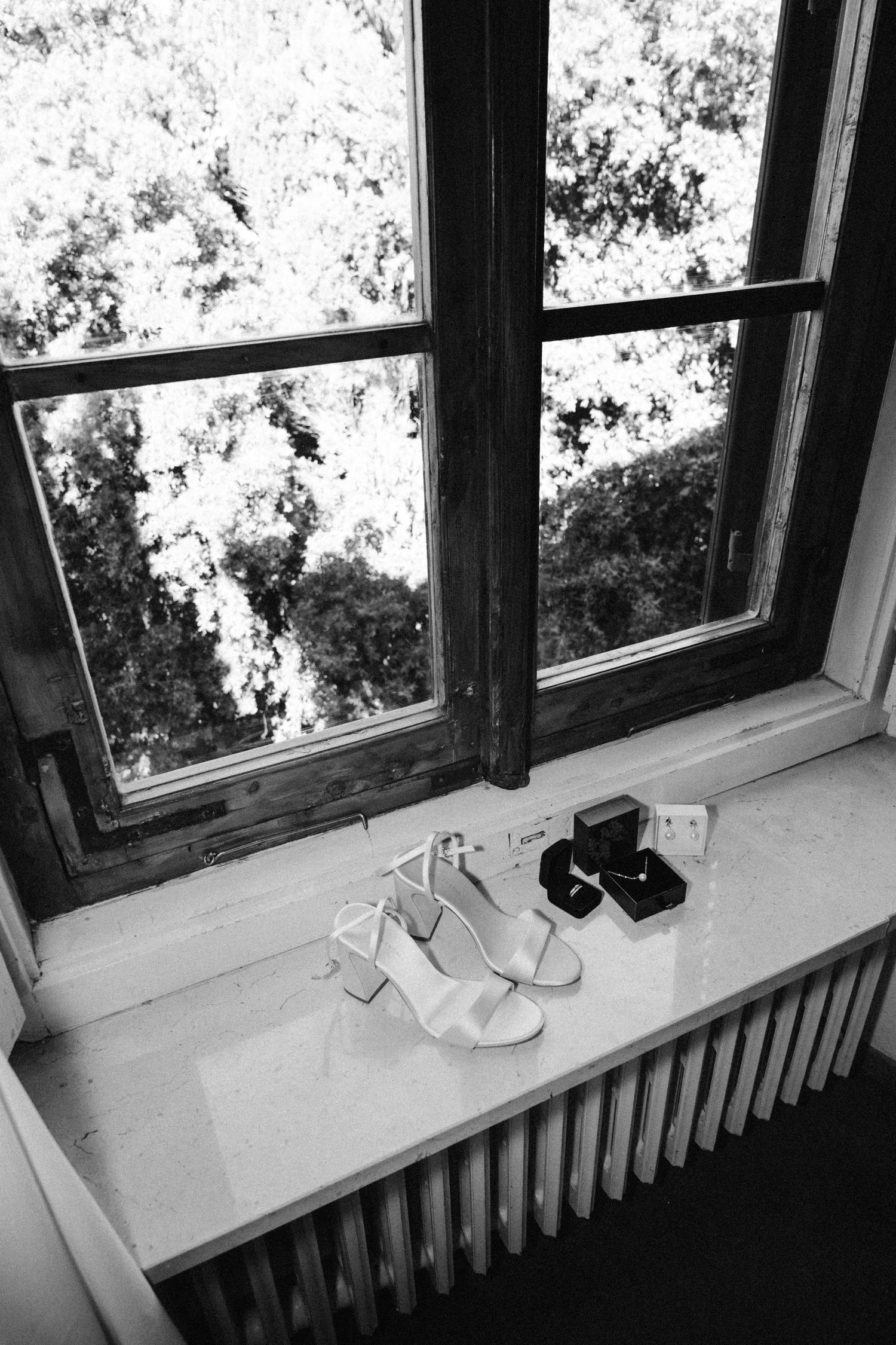 Wedding shoes displayed on windowsill with natural light streaming in.