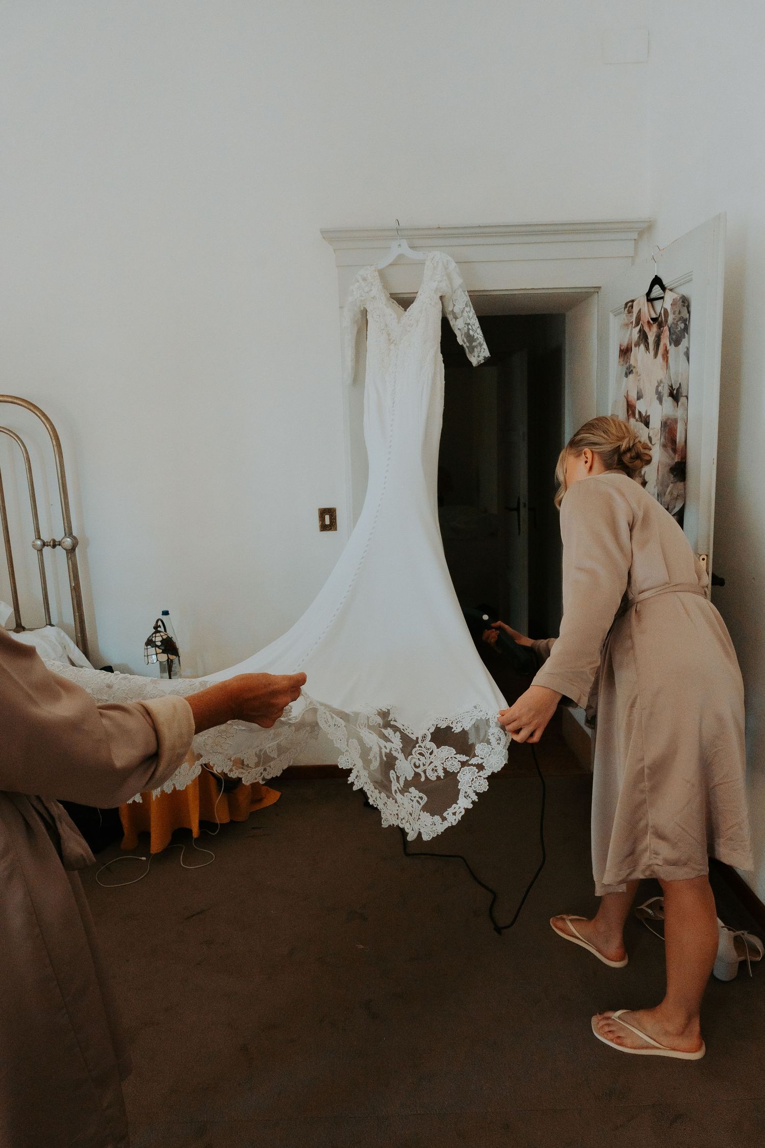 A white wedding dress displayed in a room with dark flooring.
