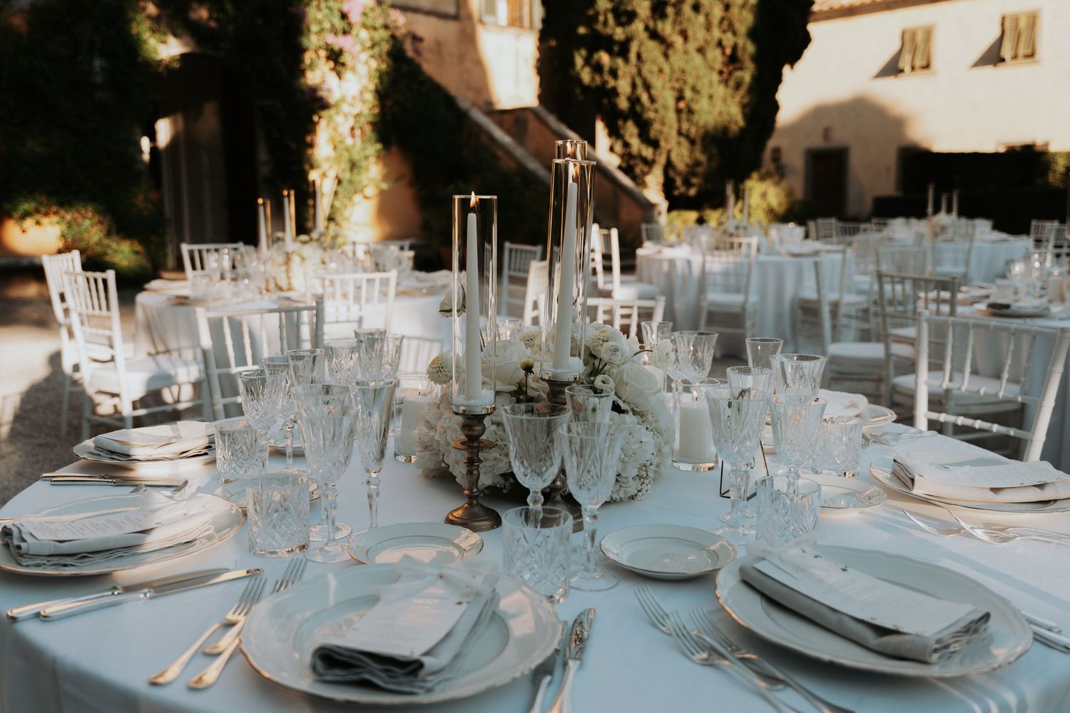 Elegant wedding reception tables set with crystal glassware and white linens.