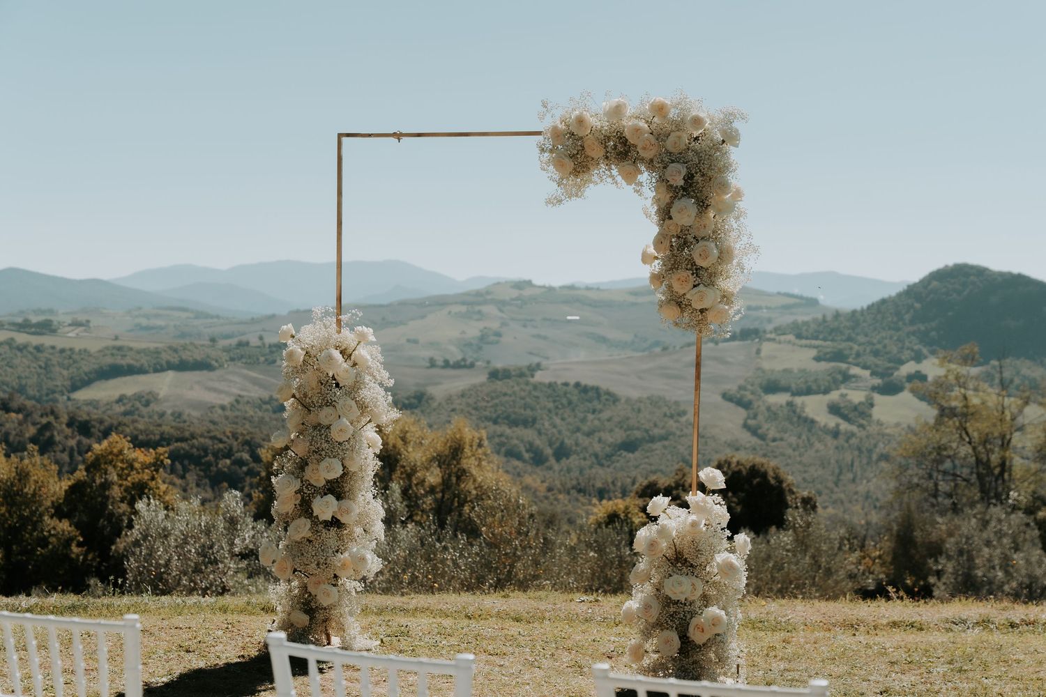 Wedding ceremony setup with floral arch and mountain landscape views.
