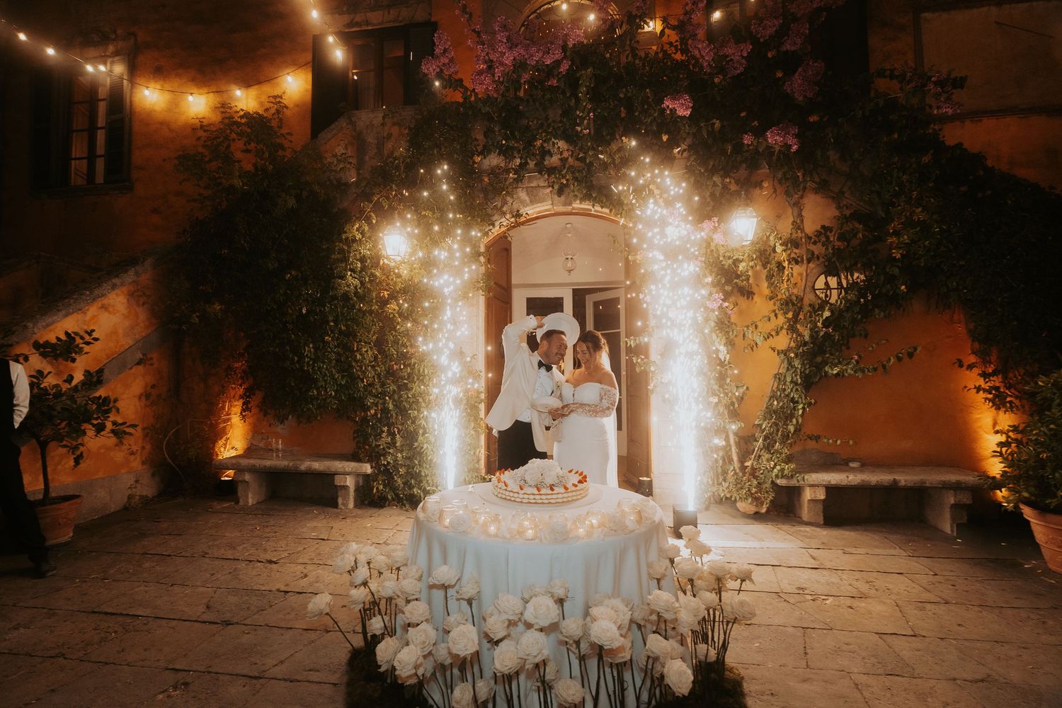 Romantic outdoor wedding venue illuminated by warm string lights and lanterns creating an enchanting atmosphere.