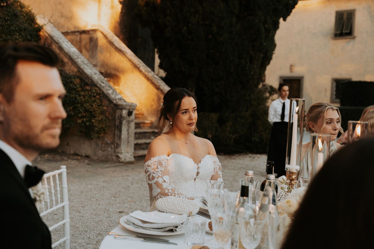 Elegant outdoor wedding dinner setup with formal place settings and ambient lighting.