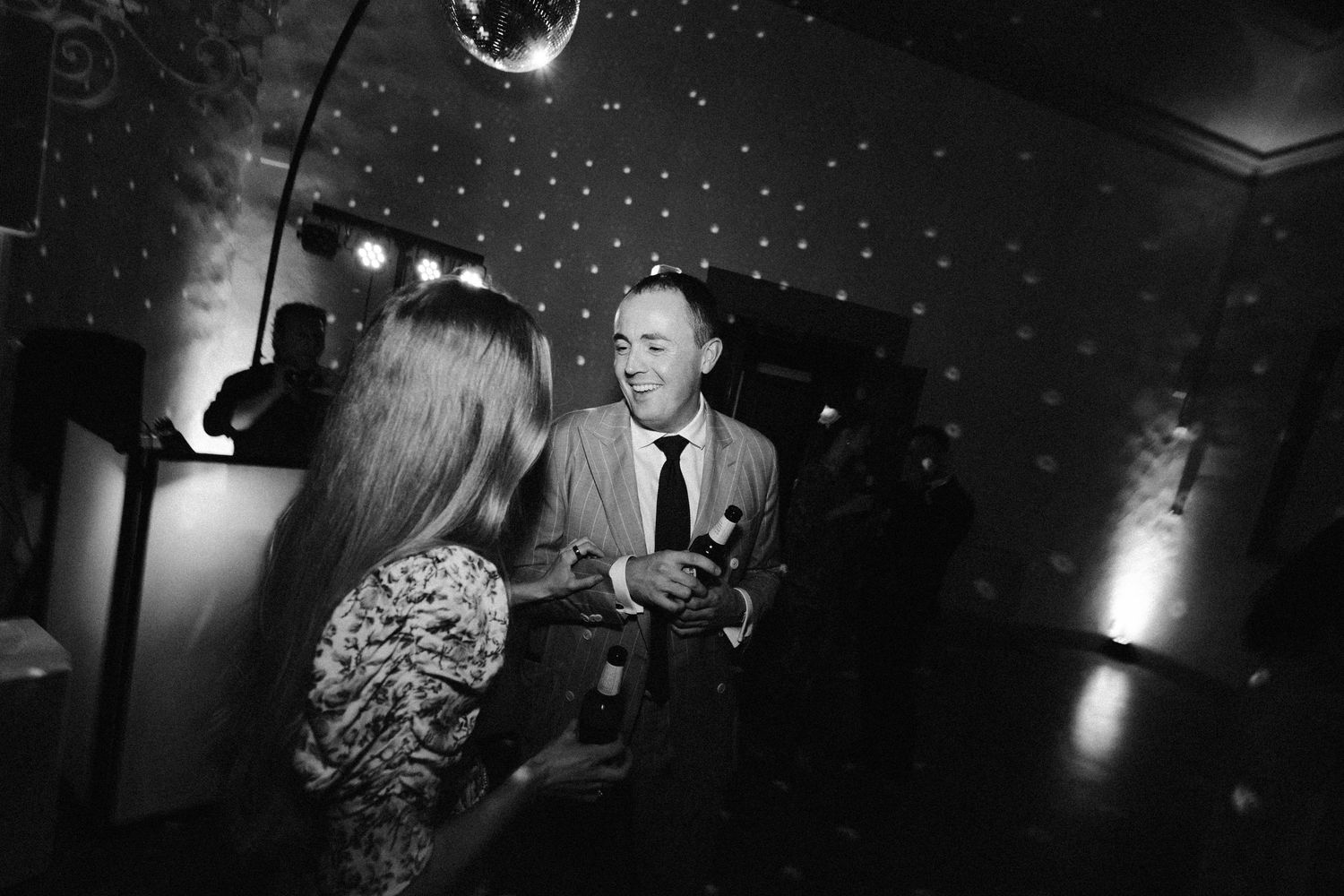A disco ball sparkles above a dark dance floor during wedding celebrations.