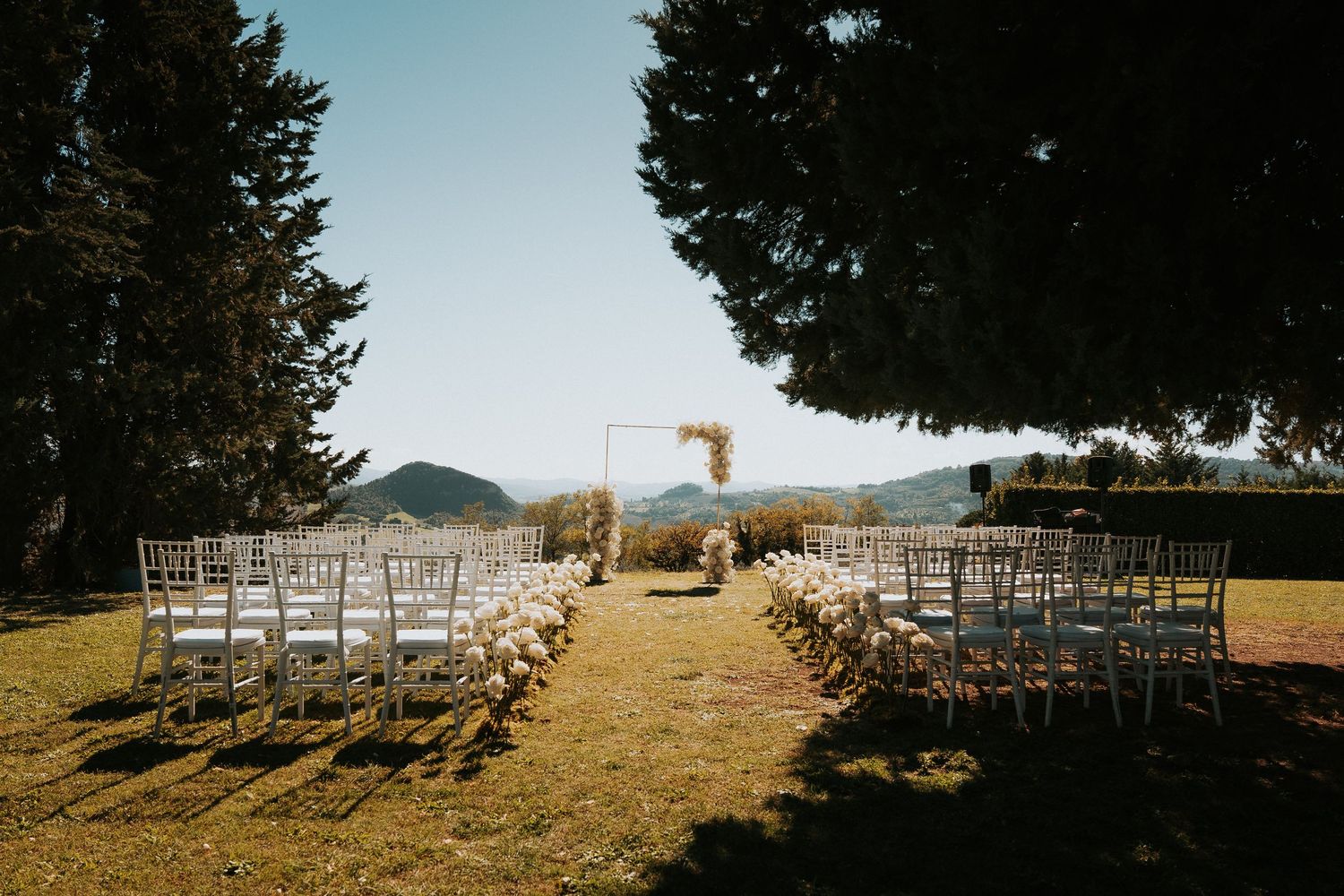 White chairs arranged outdoors for wedding ceremony with mountain vista.