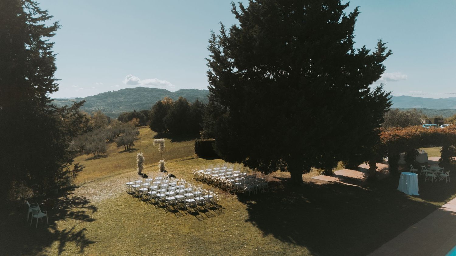Panoramic view of a hilltop wedding ceremony setup with mountain landscapes in the background.