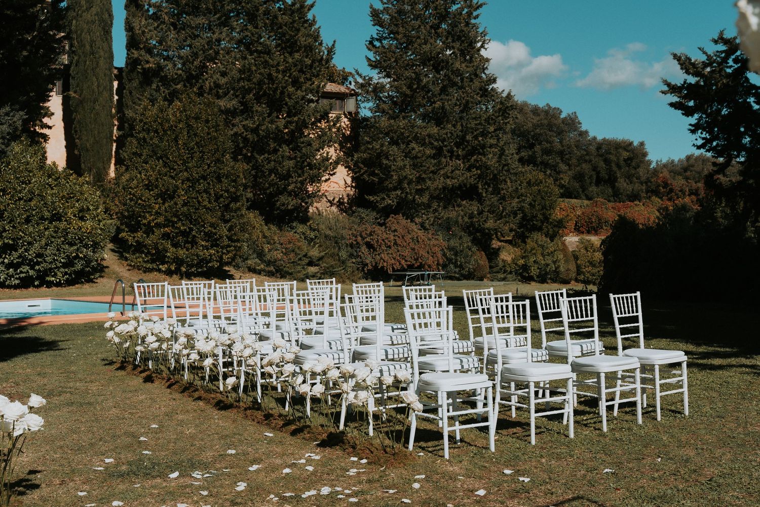 Outdoor wedding venue with white chairs arranged on hillside overlooking mountains.