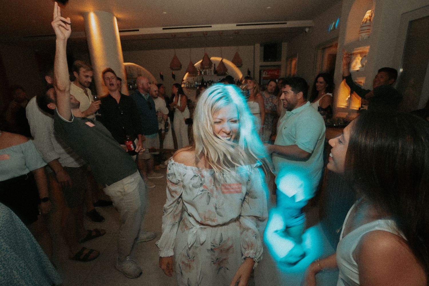 Wedding reception dance party with blue lighting and guests dancing.