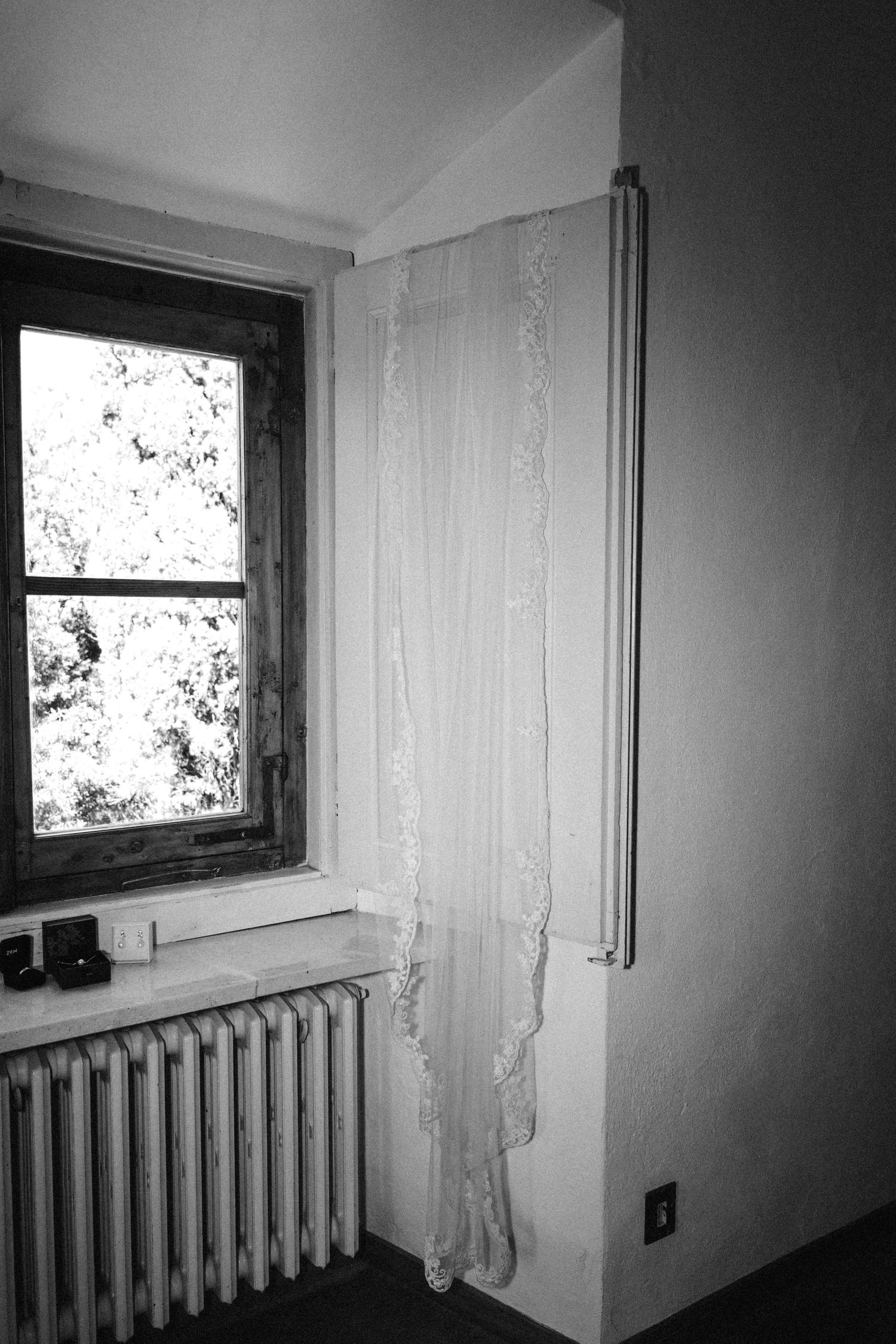 Black and white photo of a window with lace curtains and a radiator underneath.