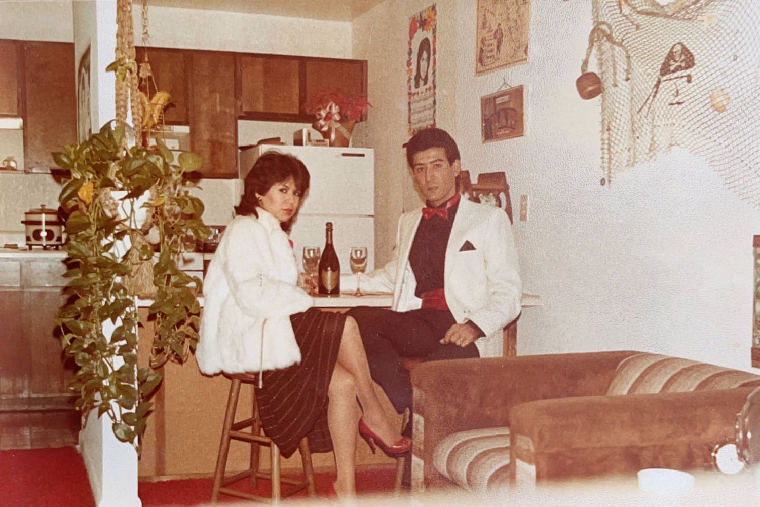 A retro photograph of a couple sitting at a home bar with 1970s decor and furnishings.
