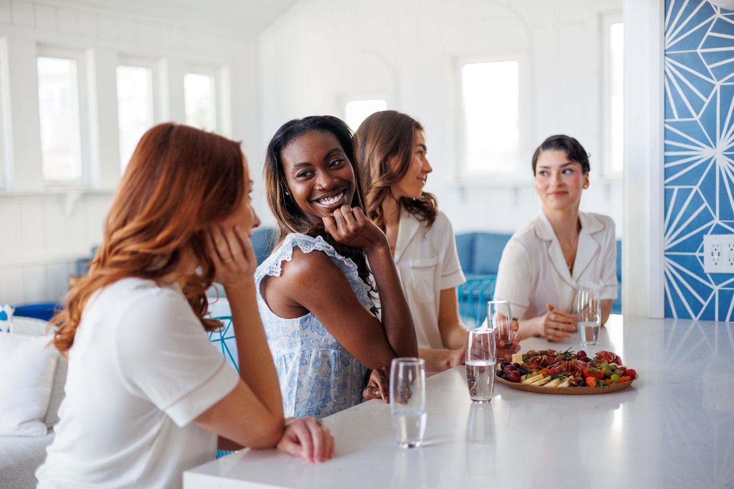 A group of friends gather around with drinks and snacks, laughing and enjoying each other's company. bridesmaids, amesbury massachusetts
