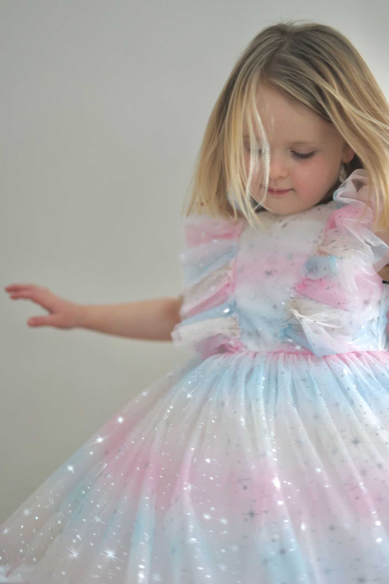 A young child twirls in a sparkly pastel pink and blue princess dress with tulle and glitter details. north shore massachusetts
