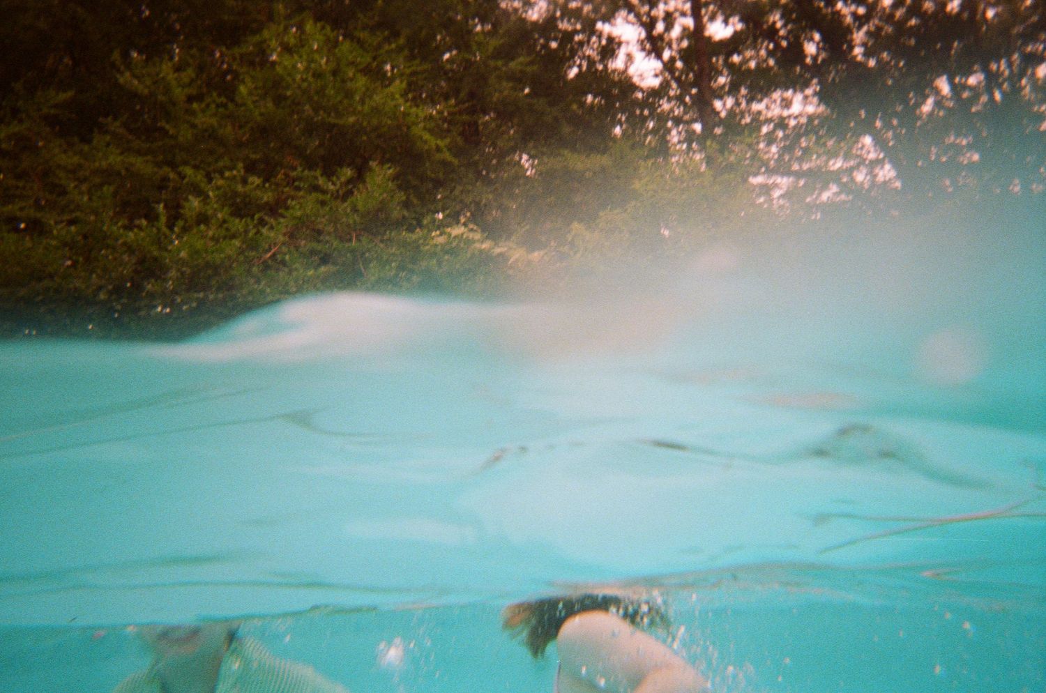 children swimming through a crystal clear turquoise pool water at sunset creating a stunning silhouette. north shore massachusetts