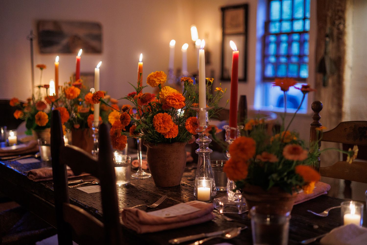 Cozy candlelit dining table with orange flowers and lanterns creates a warm, romantic atmosphere in evening light. north shore massachusetts