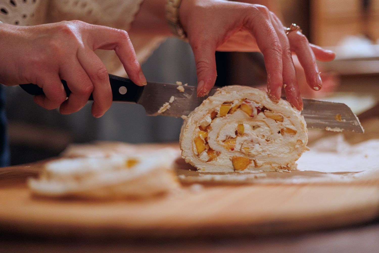Hands slicing dessert roll on a wooden cutting board in a kitchen setting. north shore massachusetts