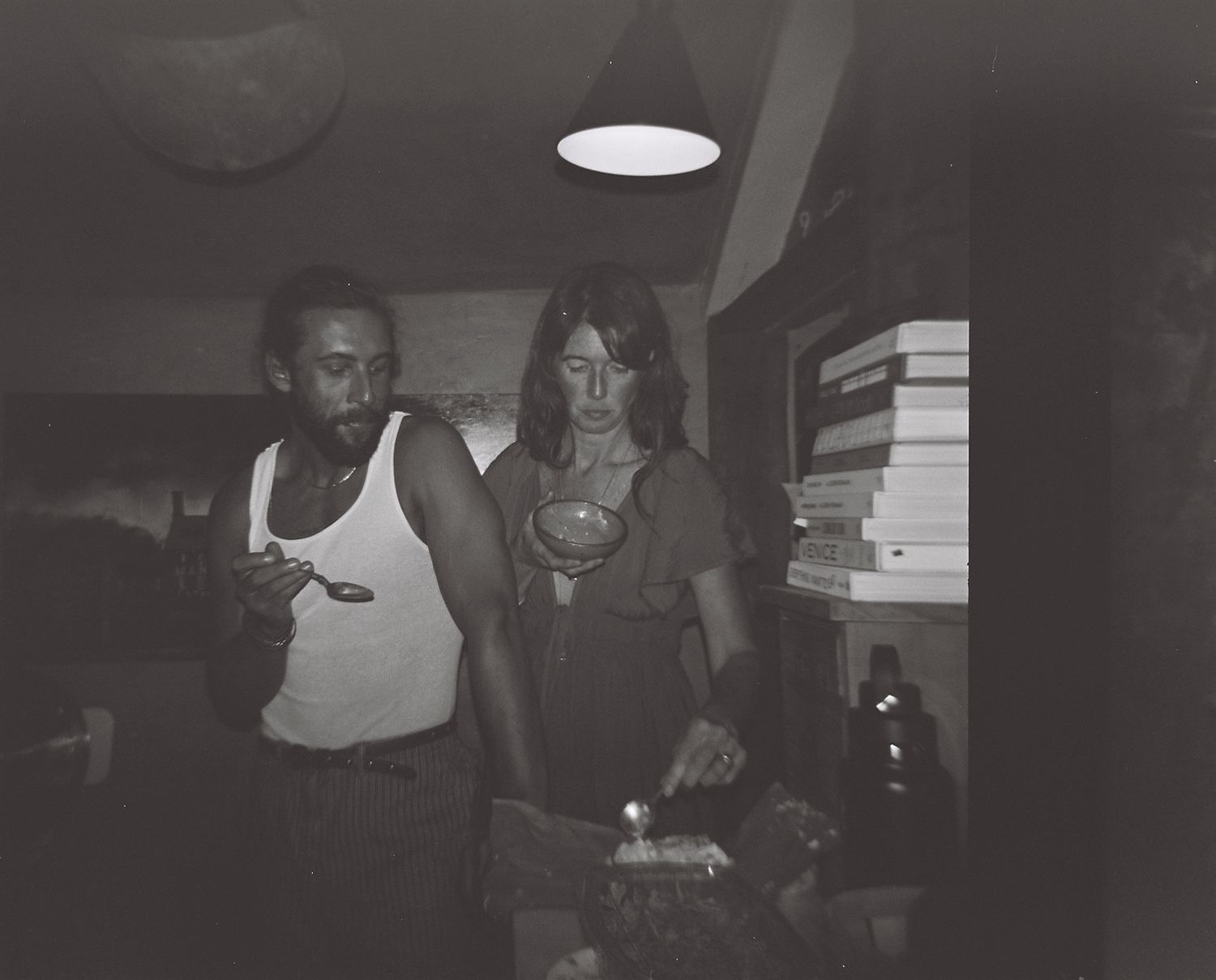 film, black and white, two adults preparing food, one eating with a spoon, north shore massachusetts