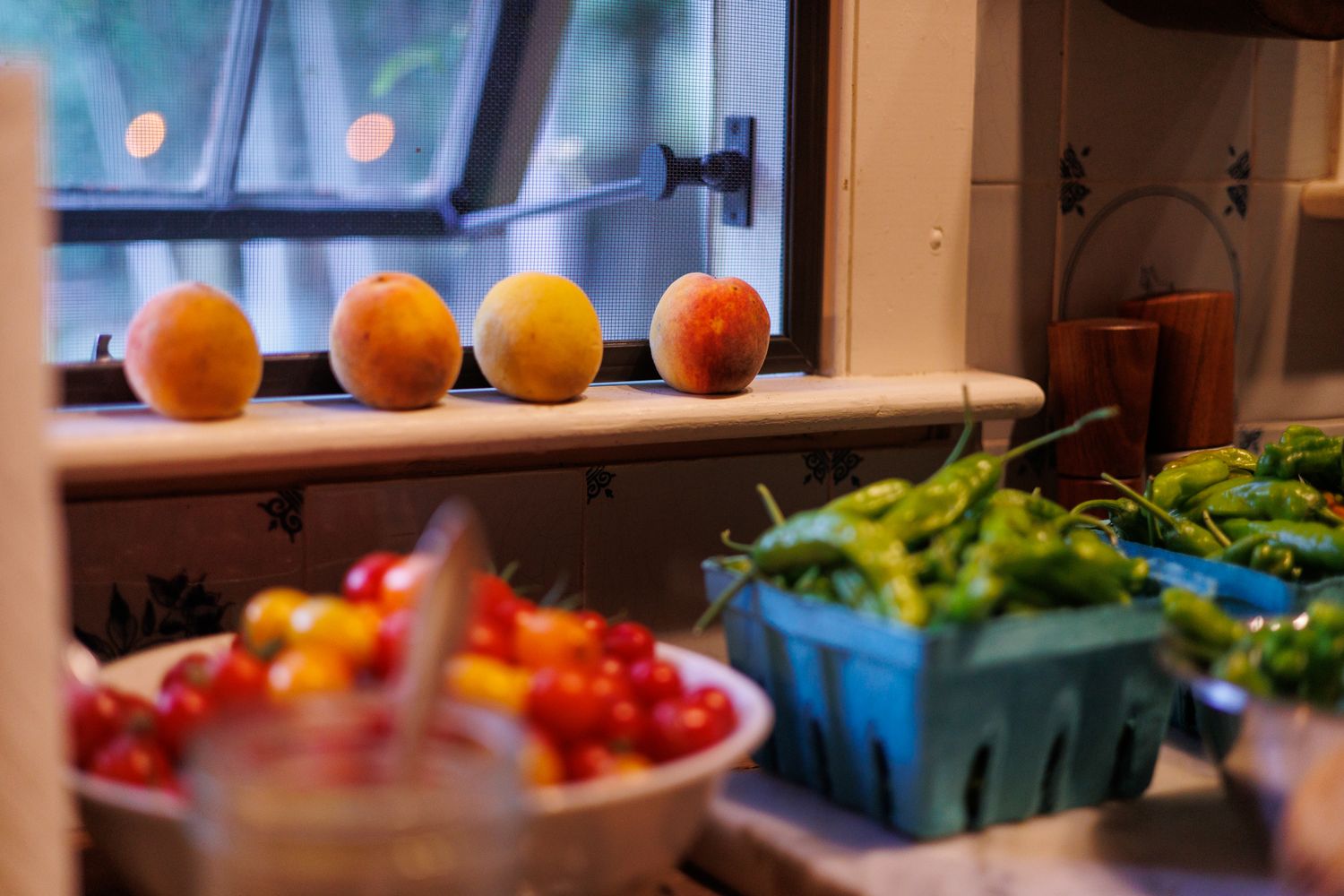 Fresh peaches on a windowsill with colorful produce in containers below, north shore massachusetts