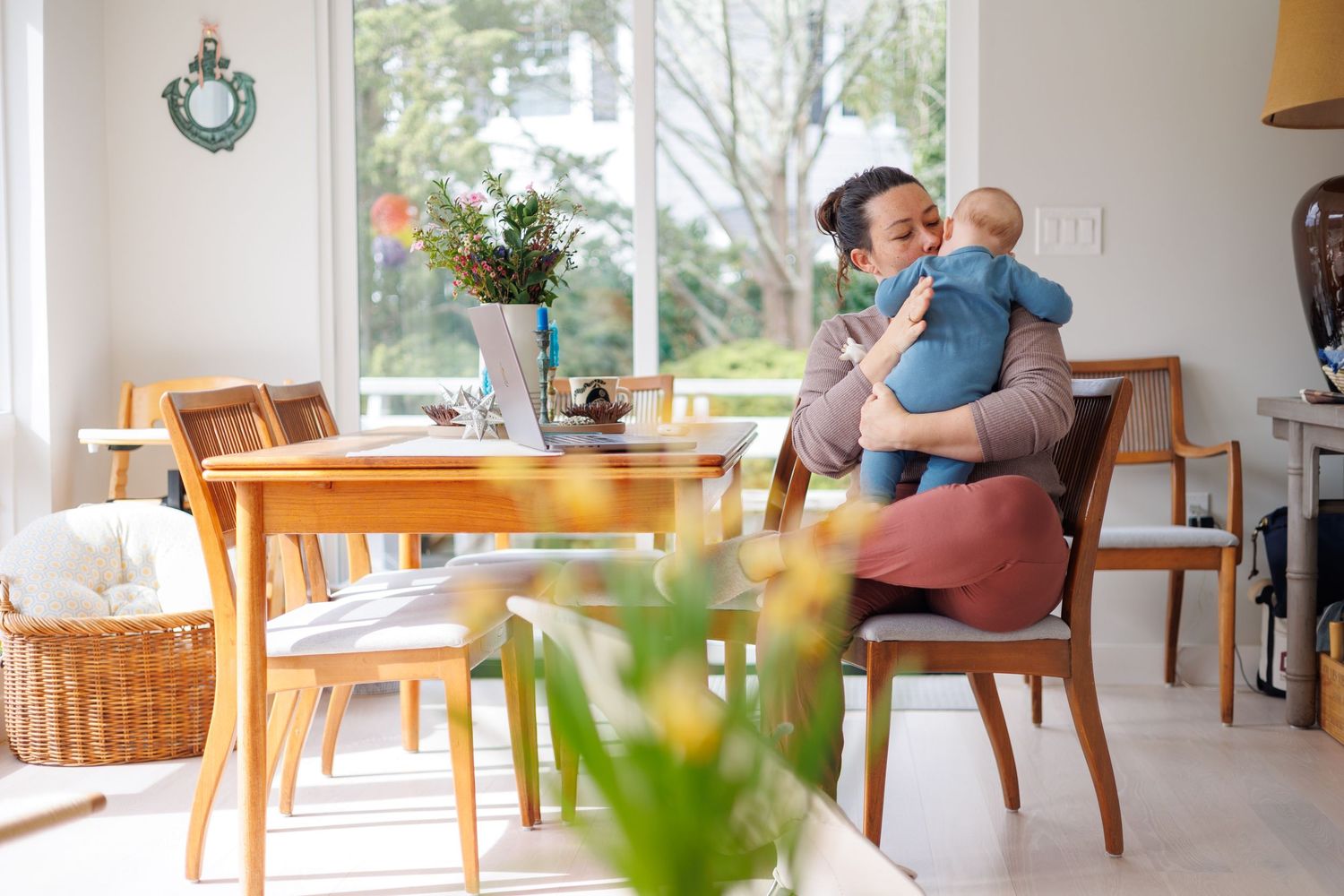 A cozy living room features mid-century modern furniture, large windows, and natural light streaming in. massachusetts, mom holding baby