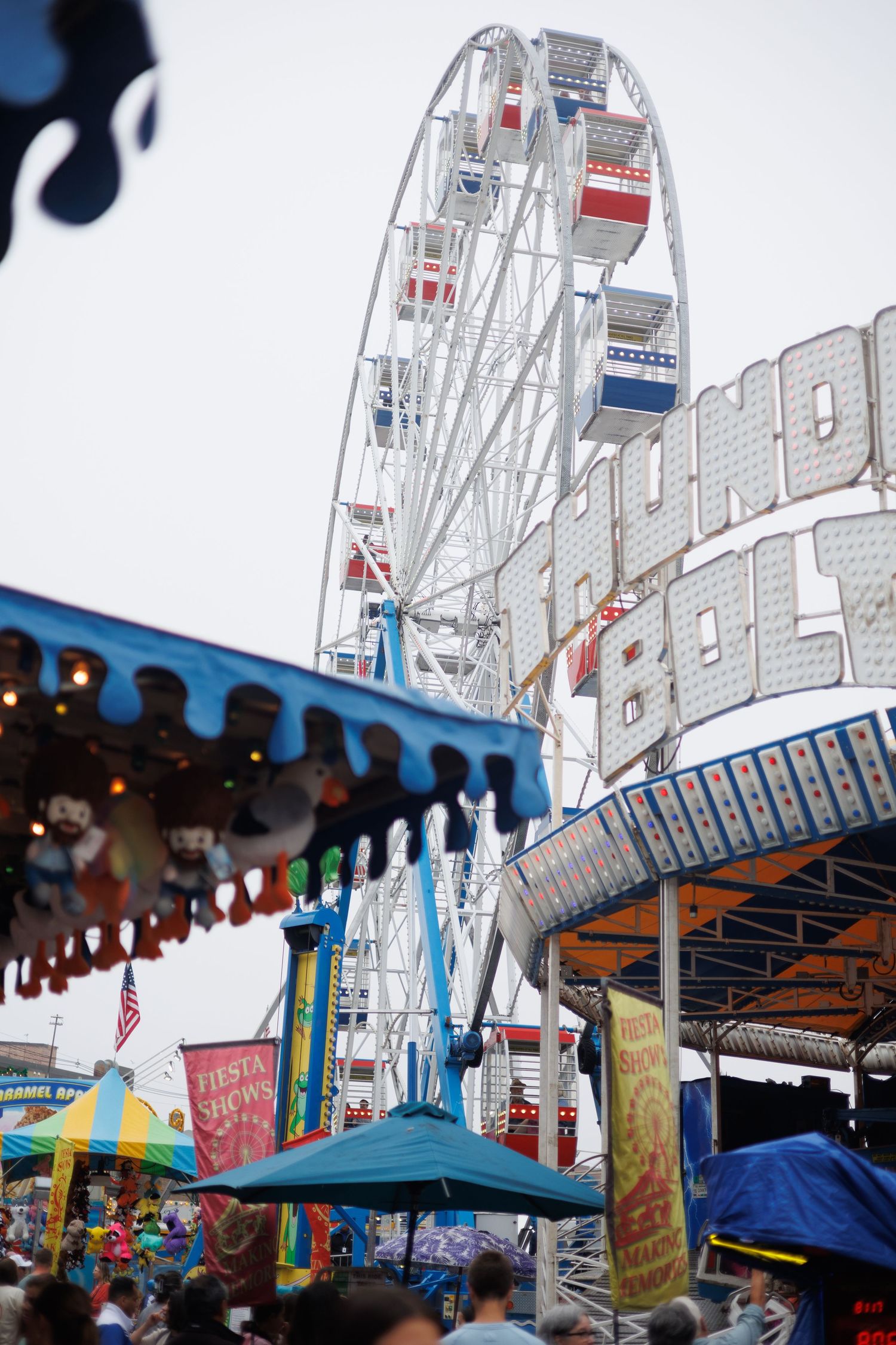 A Ferris wheel towers over carnival tents and vendor booths at a local fair with colorful decorations. gloucester massachusetts