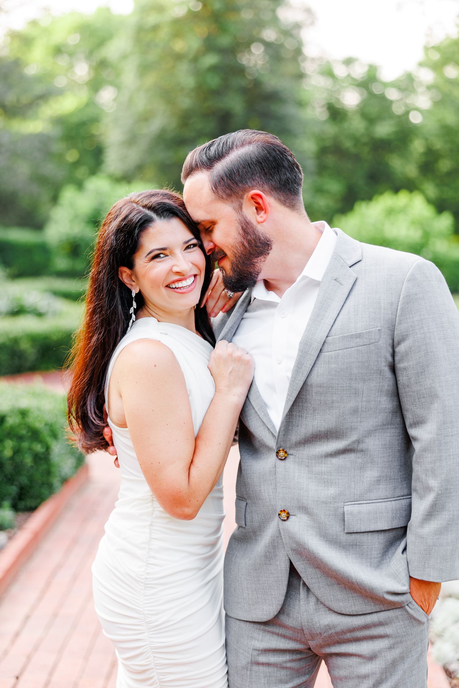 Couple sharing intimate moments in formal attire against a lush garden backdrop at Tanglewood Park