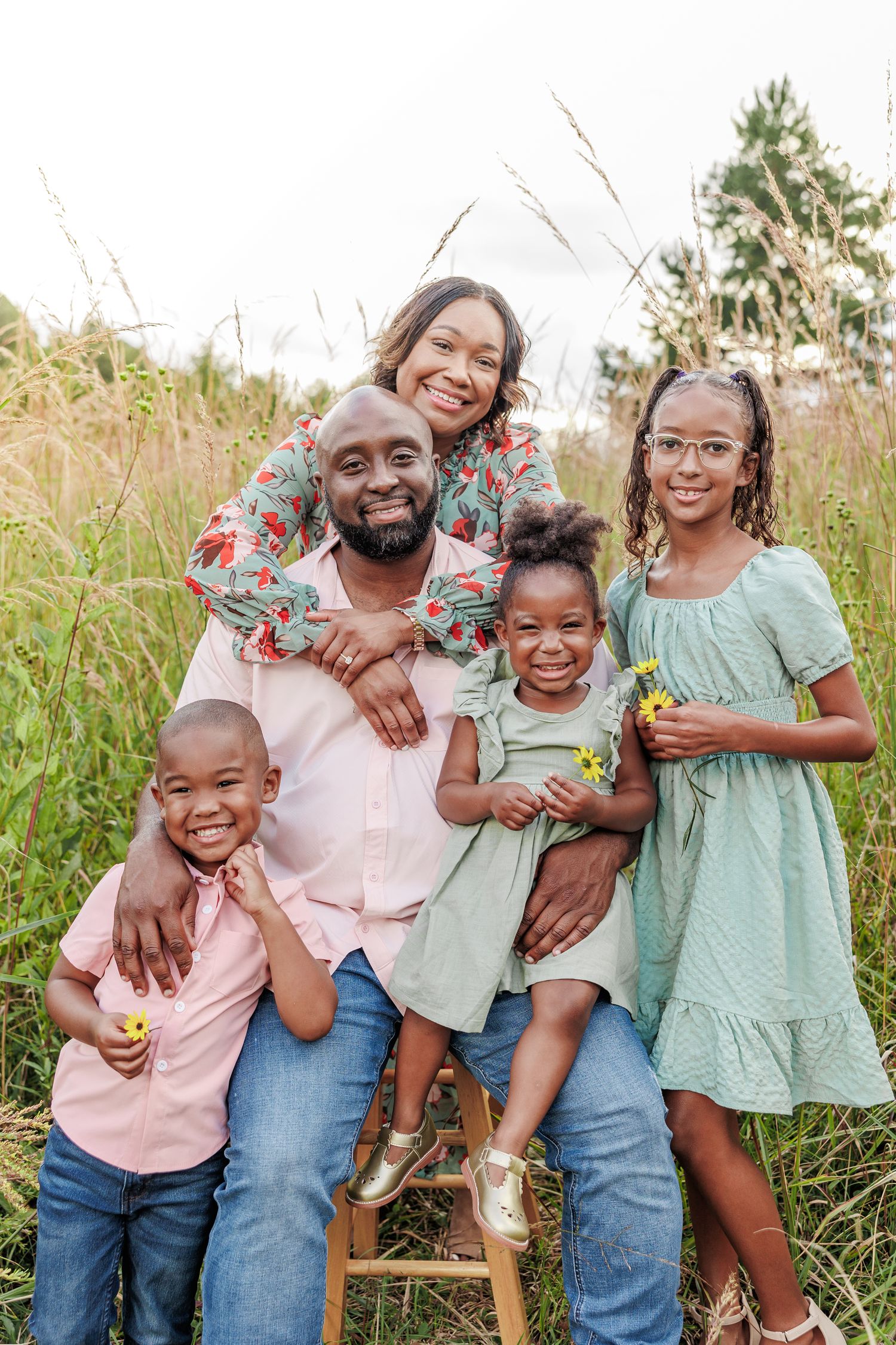 Family portrait in casual attire sitting together in natural grass setting in Greensboro NC  with a Family Photographer
