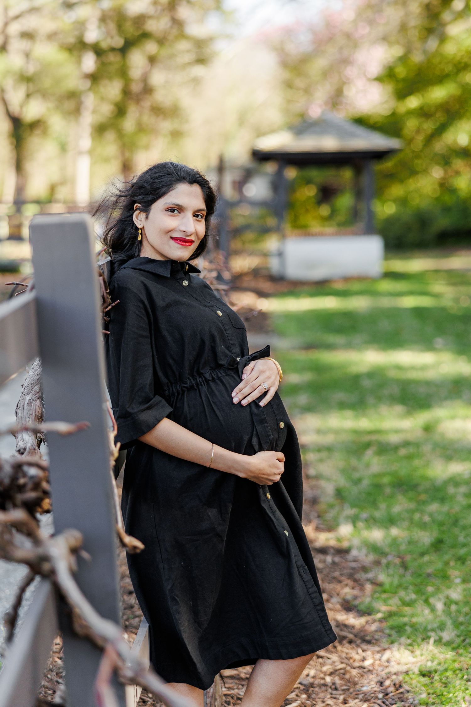 Woman in black dress poses gracefully near outdoor sculptures in Winston Salem  NC  with a Maternity Photographer