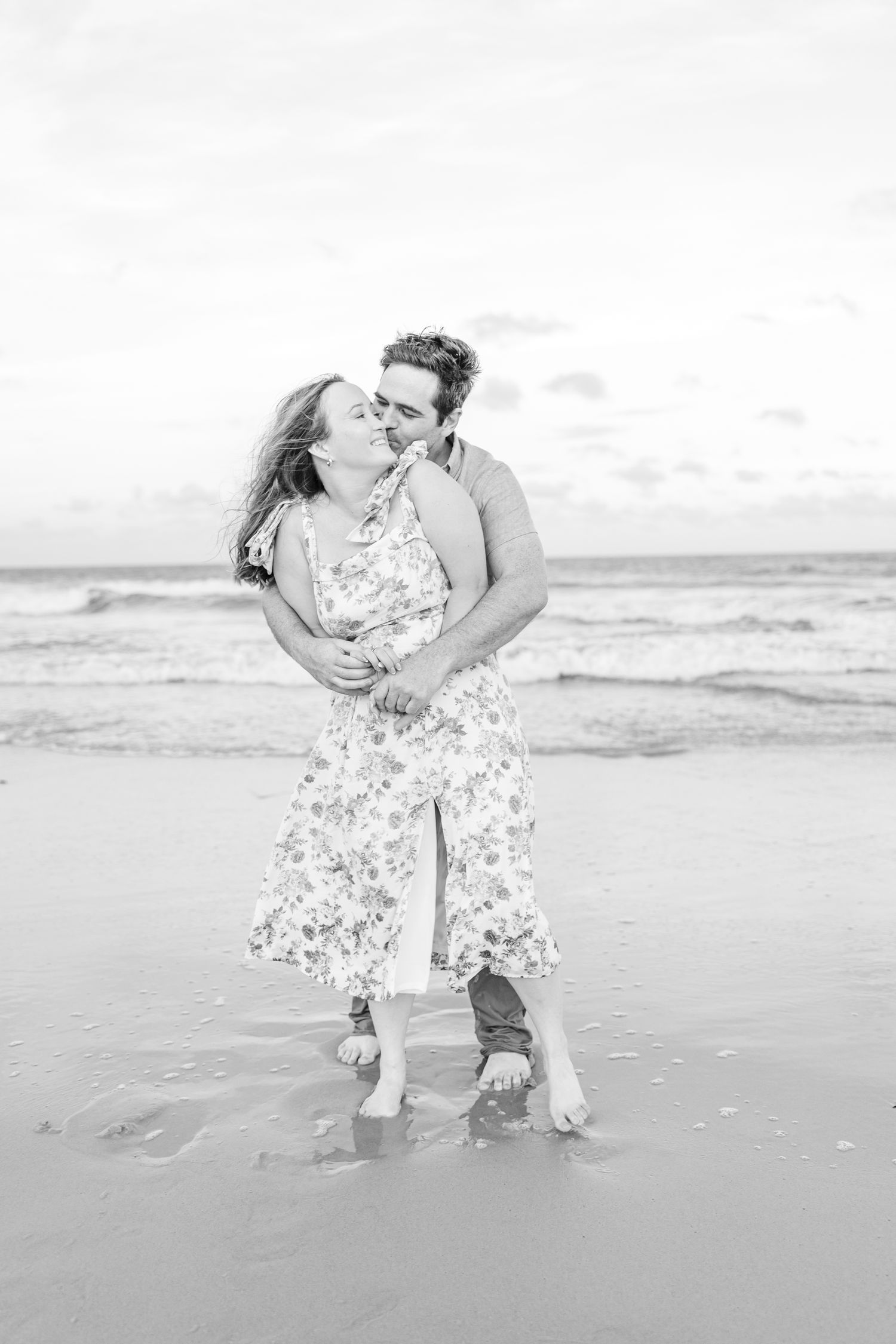 A romantic black and white photo of a couple embracing on a beach at sunset at Fort Fisher with Wilmington North Carolina Wedding Photograph