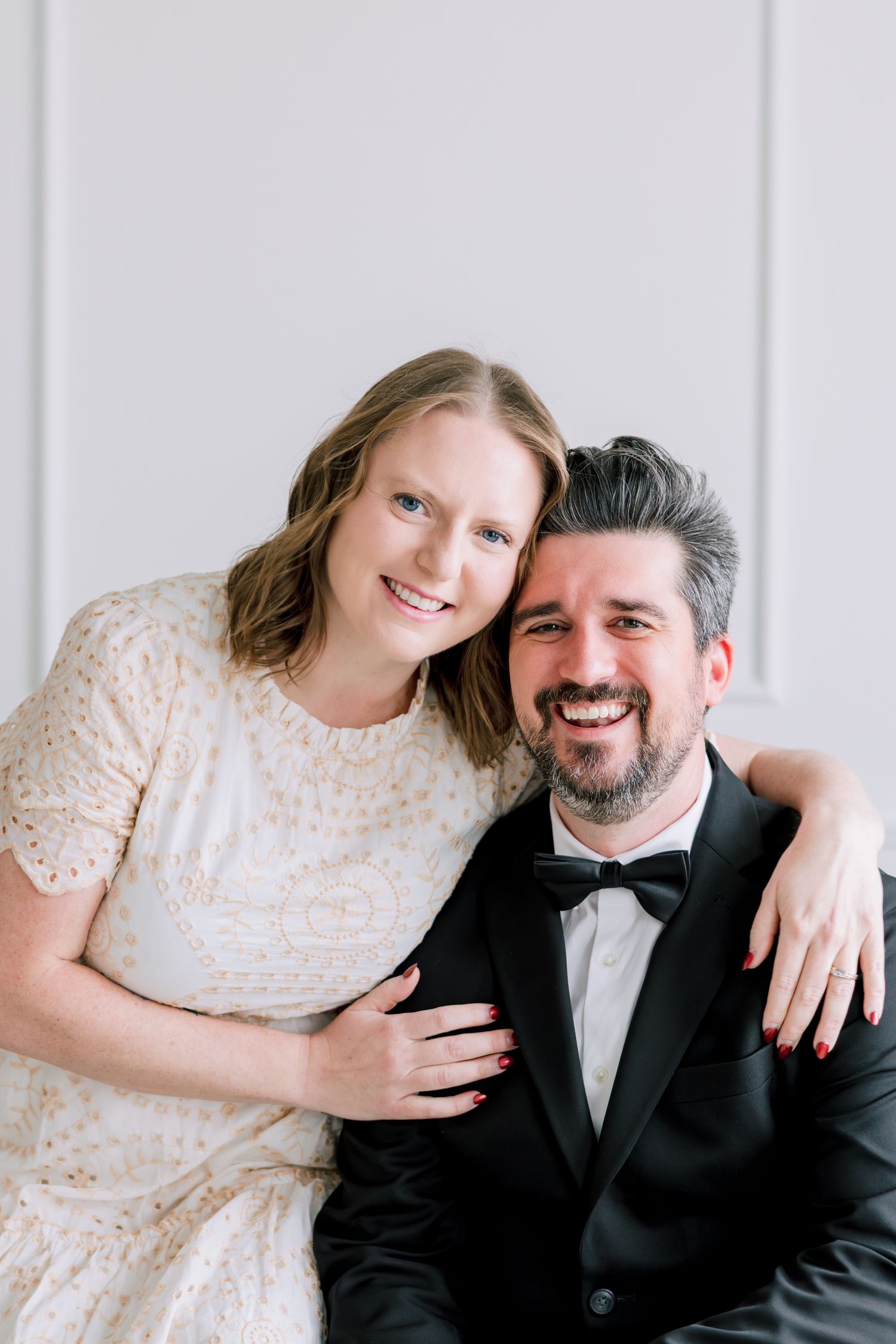 Portrait session in formal attire against classic white paneled wall.