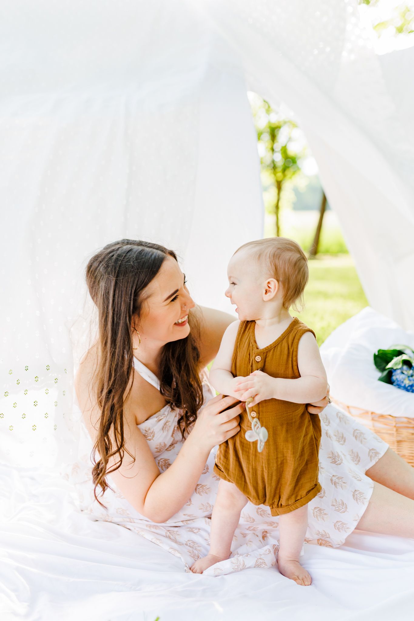 Sweet interactions between parent and baby on white blankets in outdoor setting  in Winston Salem NC  with a Family Photographer