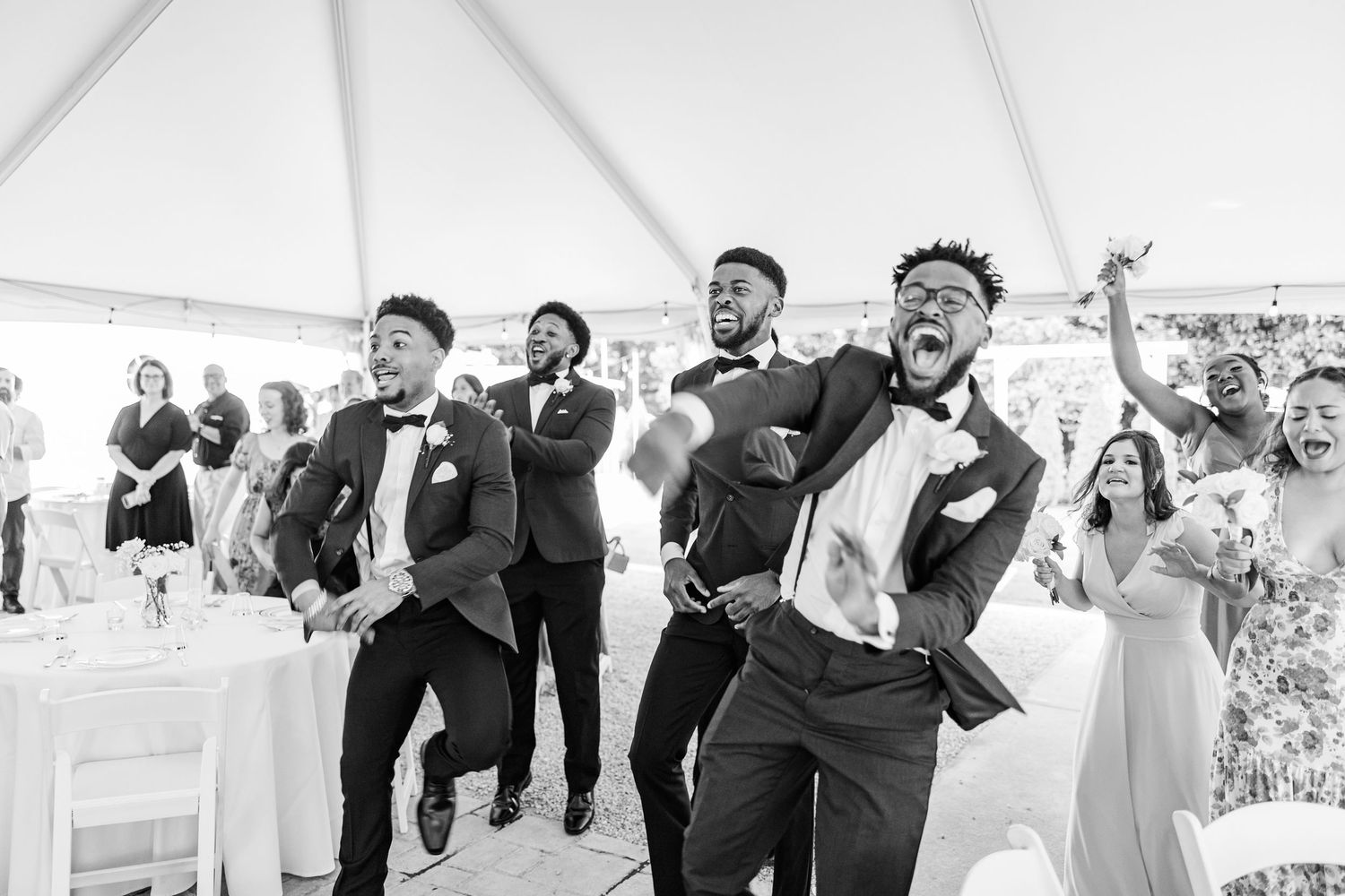 Wedding party dances and celebrates joyfully under a white tent at an outdoor reception at the Finch House in Thomasville