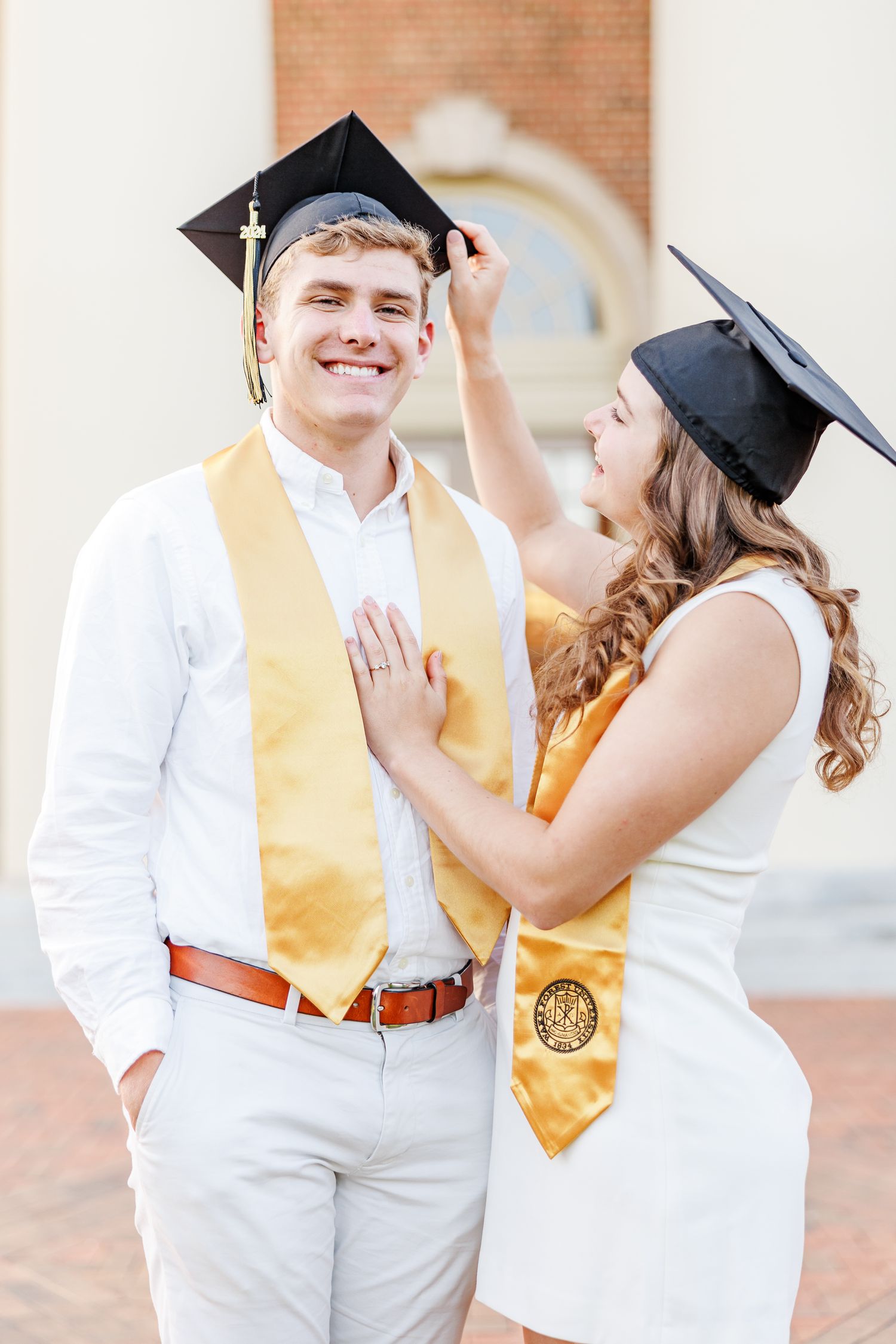 Graduates in caps and gowns share joyful moment during graduation photo session at Wake Forest University with a Graduation Photographer