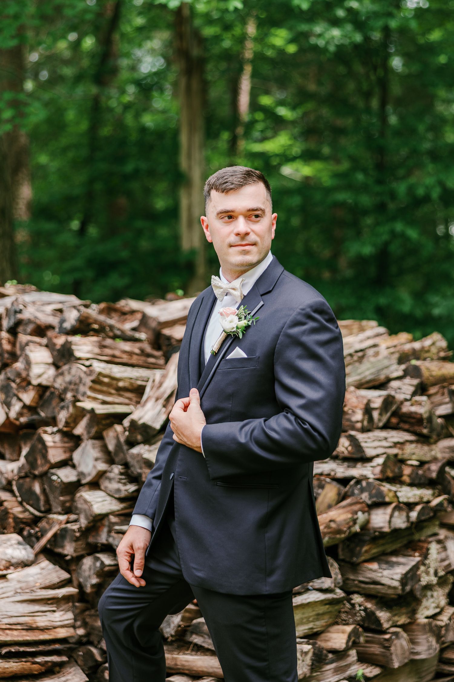 A formal portrait taken against a rustic woodpile backdrop with Winston Salem Wedding Photographer