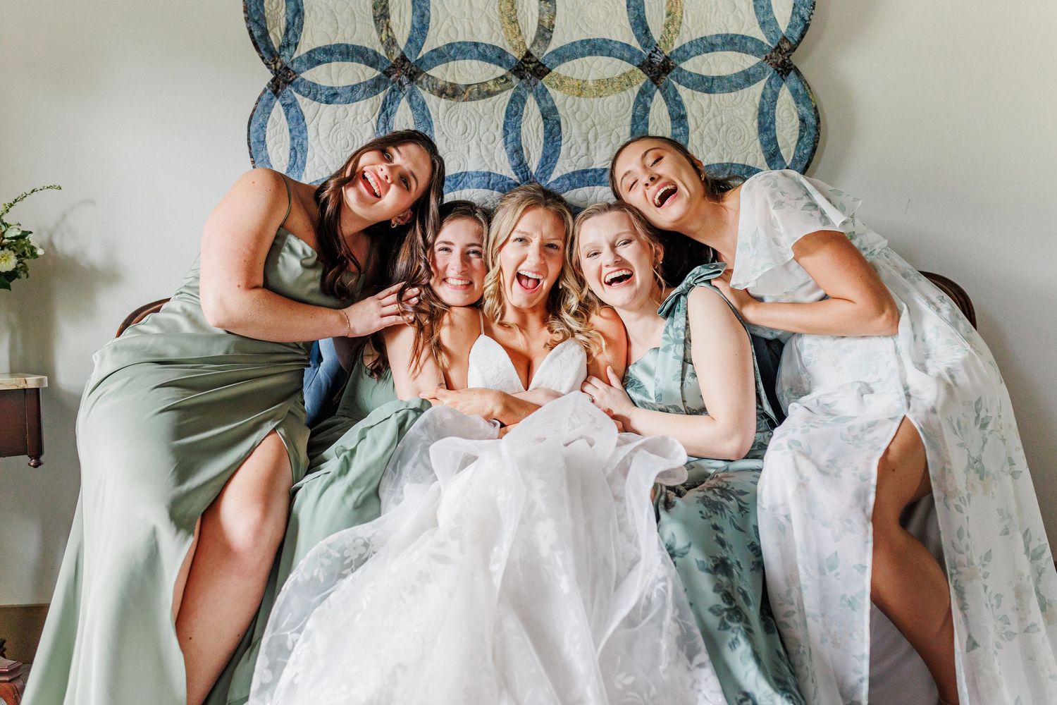 Wedding party lounging together on blue couch with patterned wall backdrop.