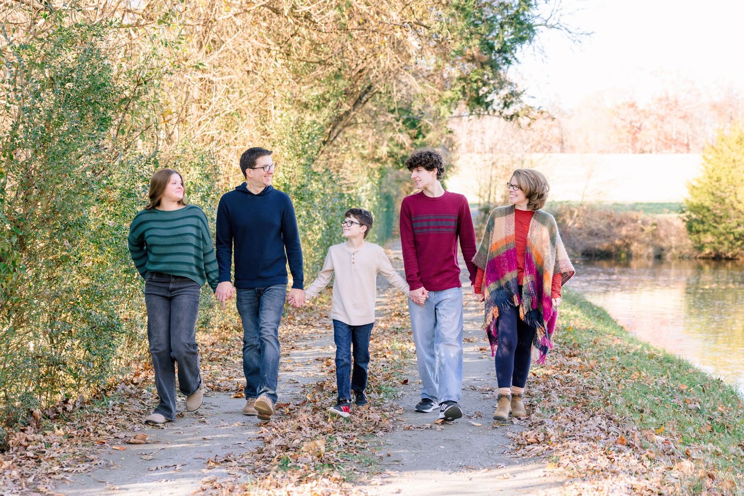 Family walking together on autumn path with trees in background in Summerfield NC  with a Family Photographer