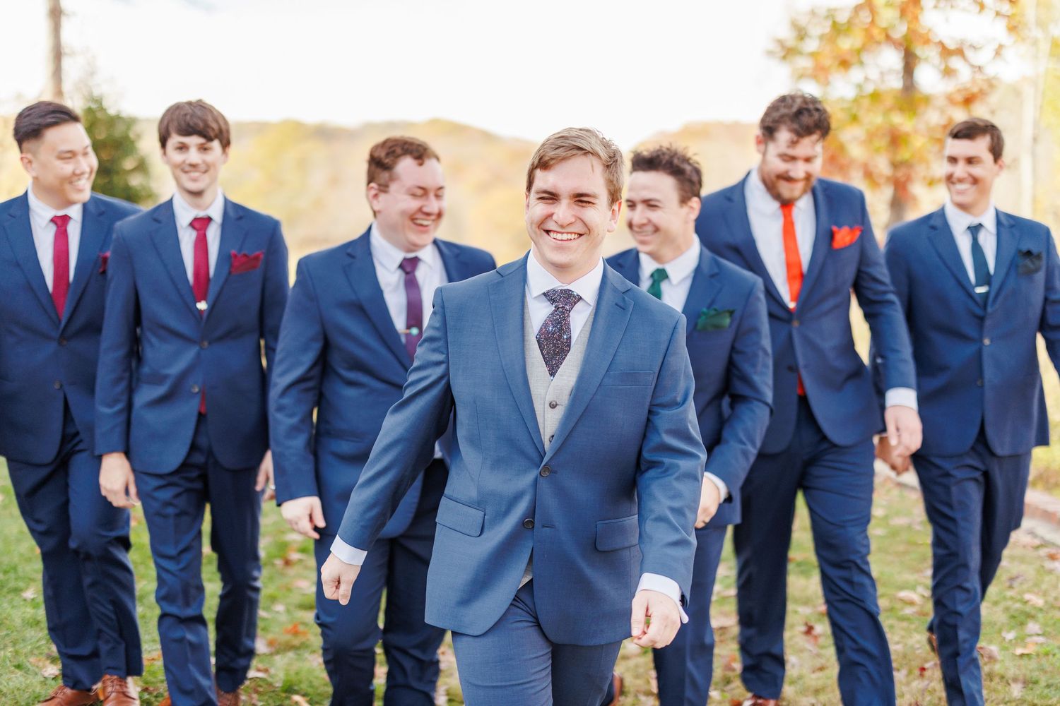 Groomsmen in navy suits pose together outdoors during wedding day with North Carolina Wedding Photographer