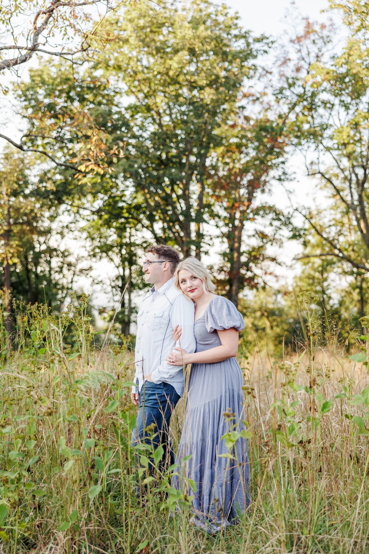 A couple stands together in a wildflower meadow during golden hour with Winston Salem Engagement Photographer at Pilot Mountain