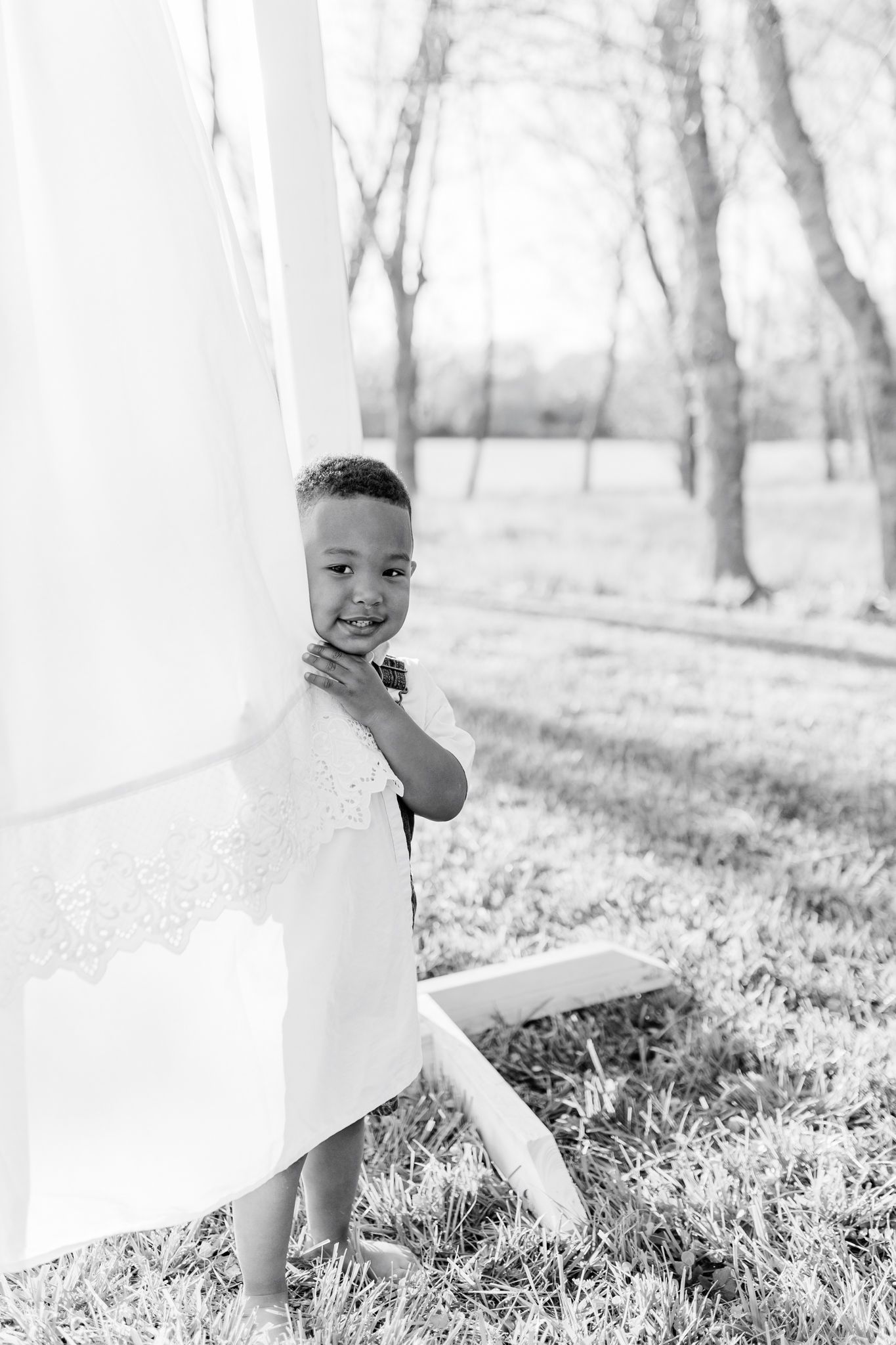 Black and white portraits of baby playing among flowing white curtains outdoors  in Winston Salem NC  with a Family Photographer