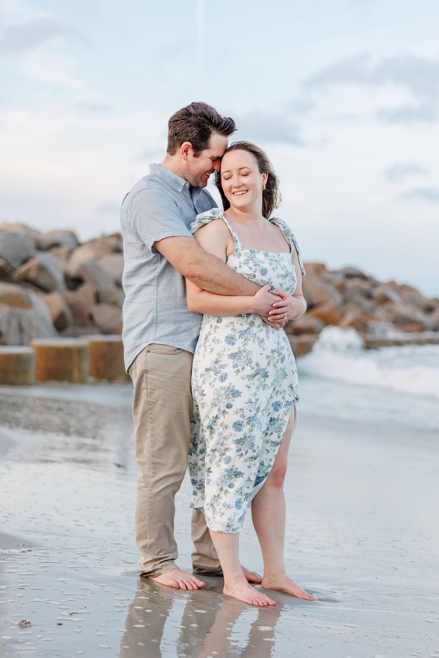 Romantic beach photoshoot with couple embracing on sandy shore at sunset at Fort Fisher with Wilmington North Carolina Wedding Photographer
