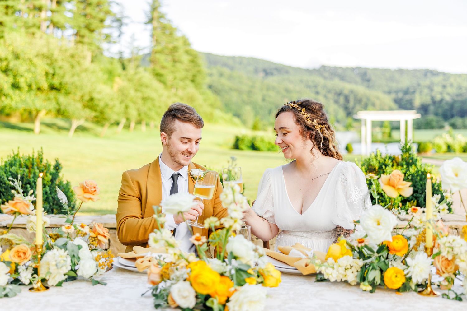 Wedding table setting with yellow and white floral arrangements outdoors.