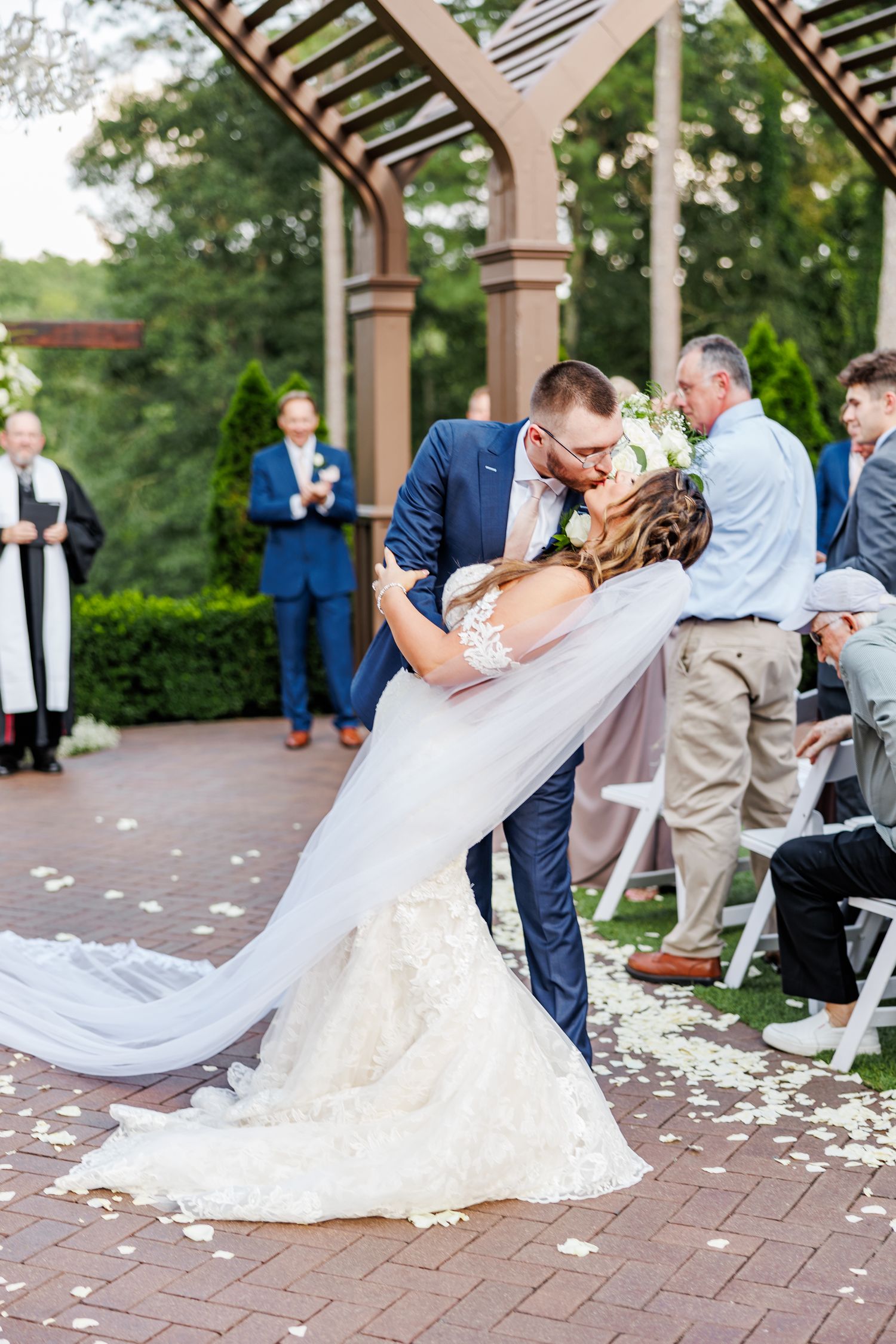 Newlyweds share intimate dance dips on a brick patio covered with flower petals at the High Grove Estate