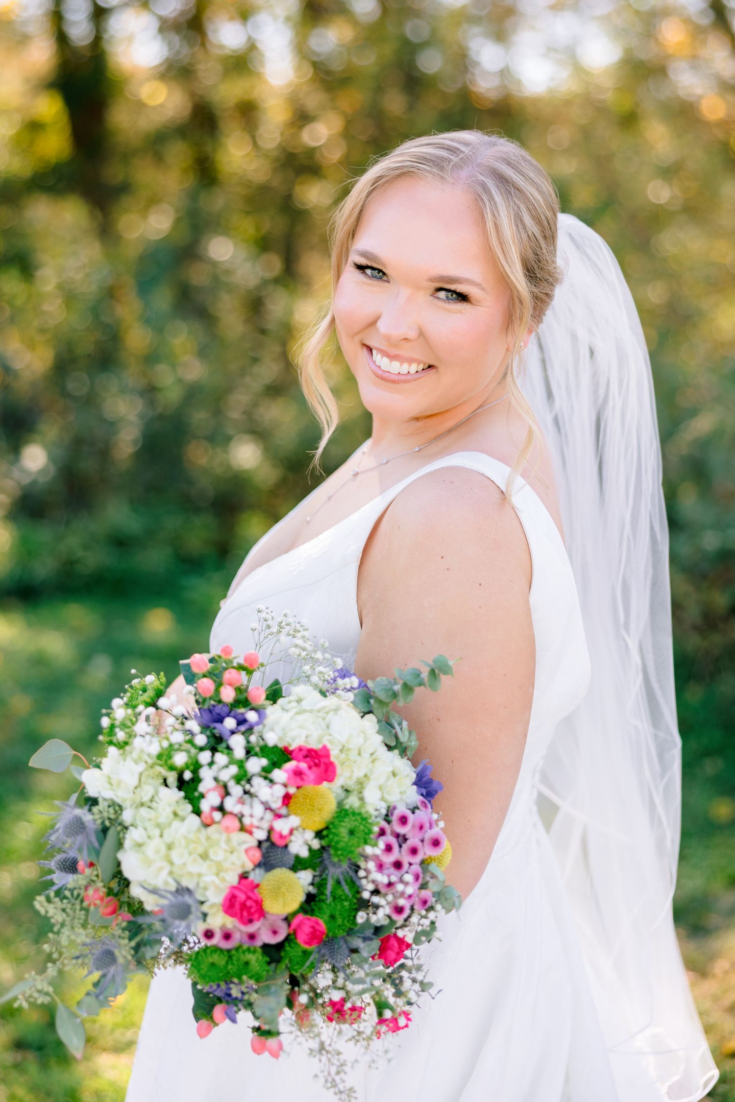 Colorful bridal bouquet featuring pink, purple, and white flowers against white wedding dress with Winston Salem Wedding Photographer