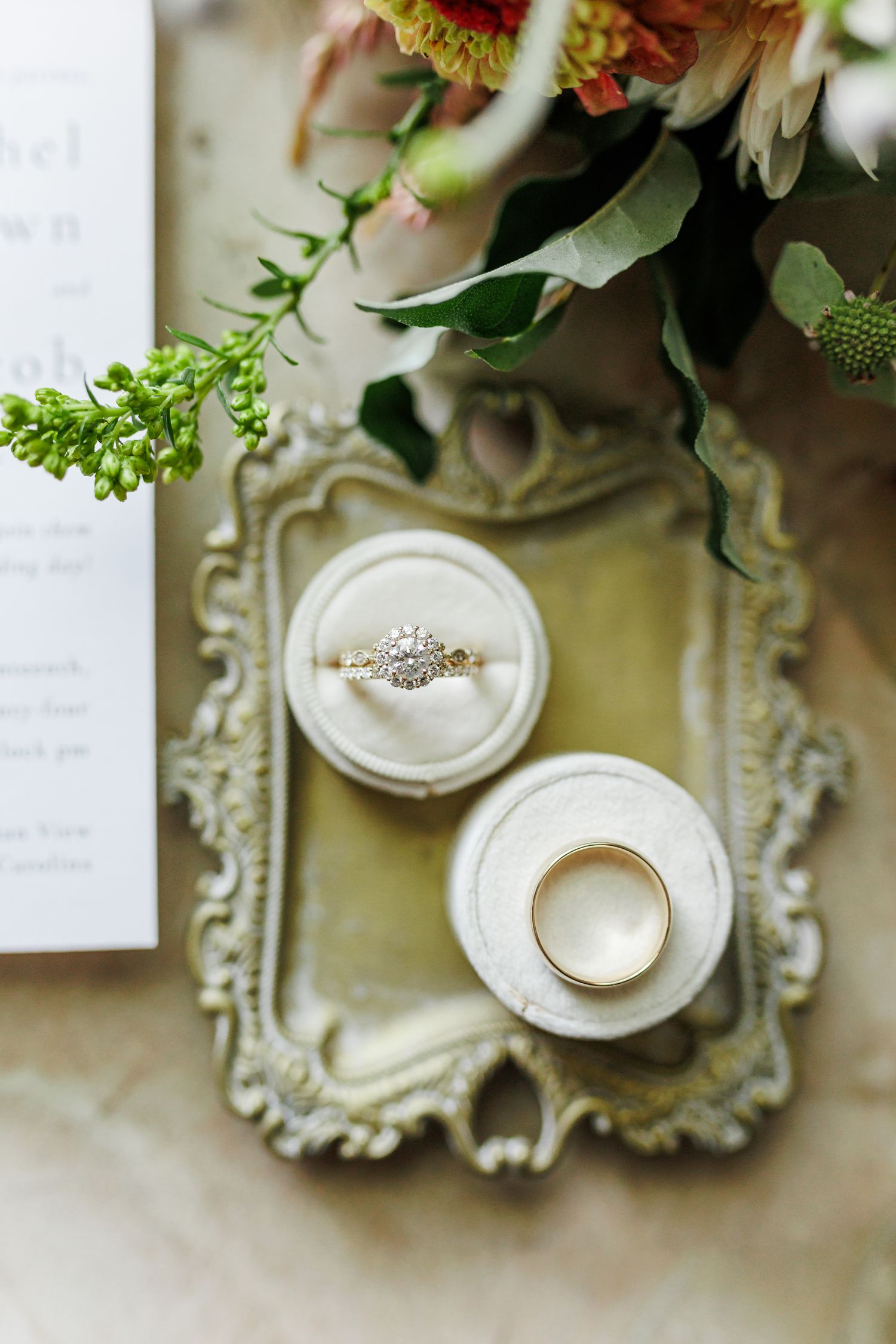 Wedding rings displayed in ornate white ring boxes with floral arrangements above at Appalachian View Venue with Boone Wedding Photographer