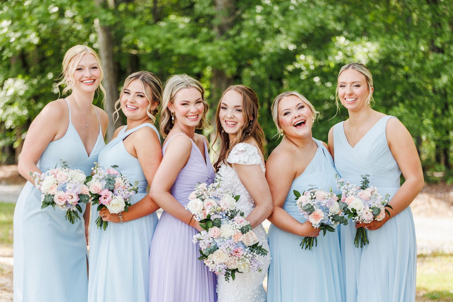 Bridesmaids in light blue dresses hold pink and white floral bouquets during an outdoor wedding ceremony with North Carolina Wedding
