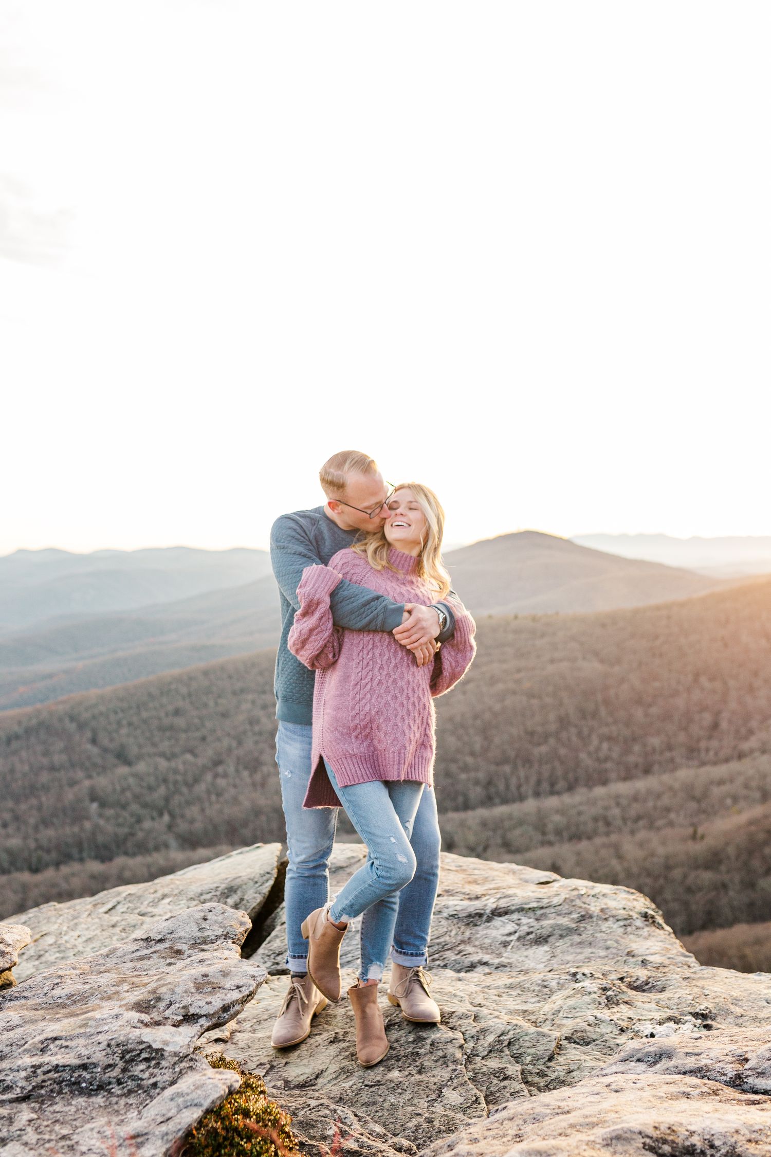 Couple sharing romantic moment on rocky mountain ledge overlooking vast wilderness Boone NC Engagement Photographer on the Blue Ridge Parkwa
